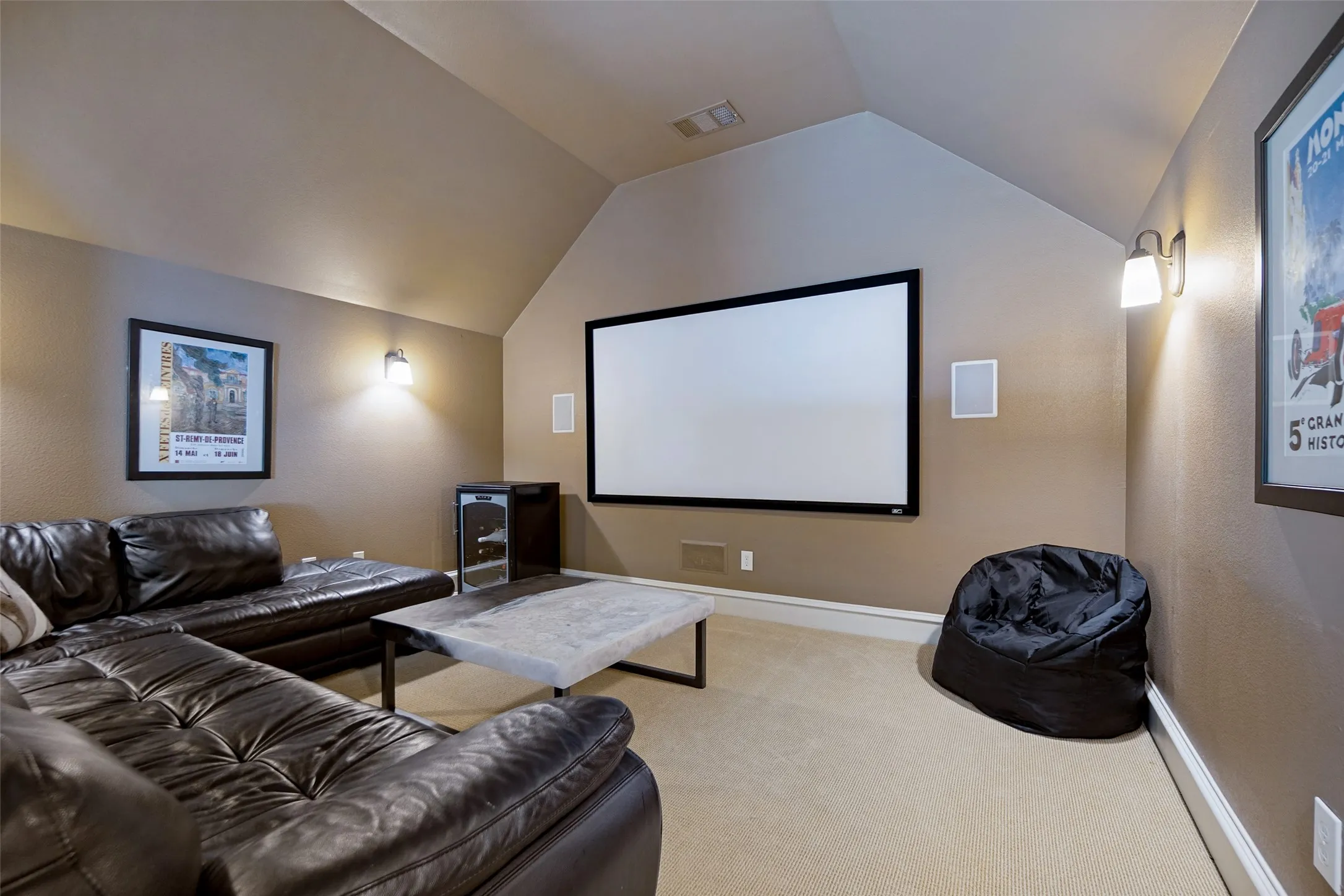 Media room featuring a large projection screen, built-in wall speakers, and sconce lighting
