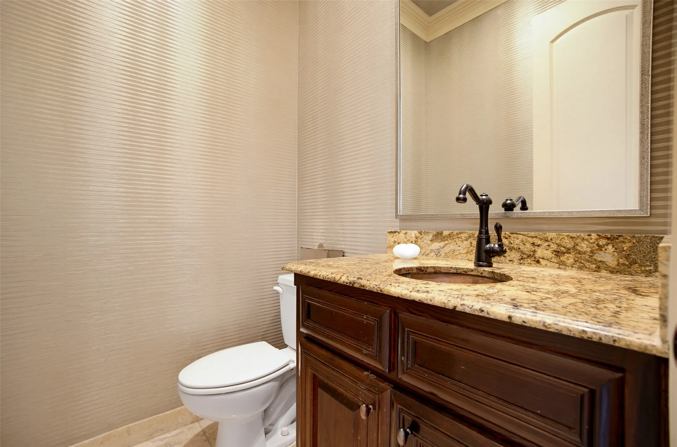 Vanity with a polished stone countertop and integrated copper basin, featuring a dark-finished faucet