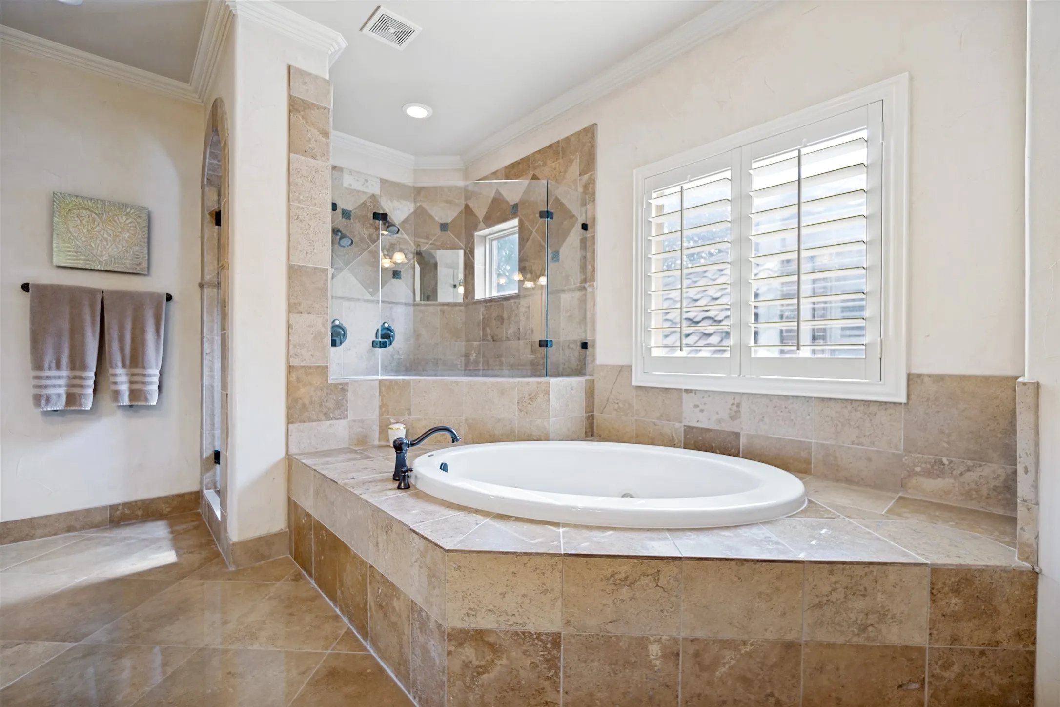 Built-in jetted tub with tile surround, paired with an adjacent glass-enclosed shower featuring multiple showerheads and a tiled backdrop