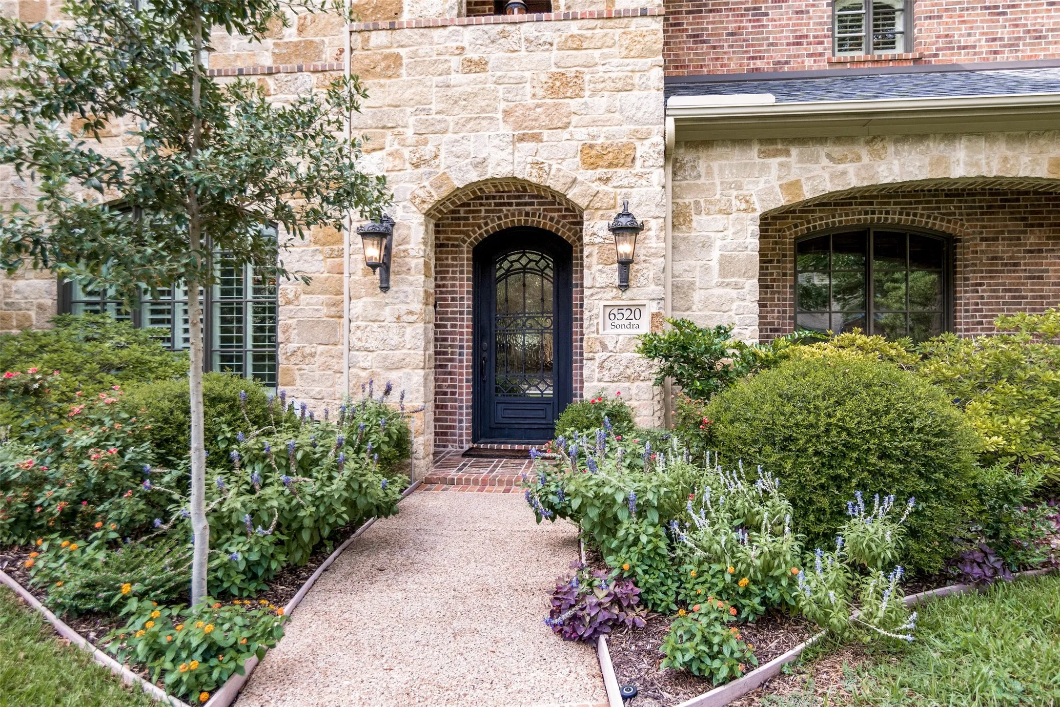 Stone and brick facade with an arched entry and wrought iron door