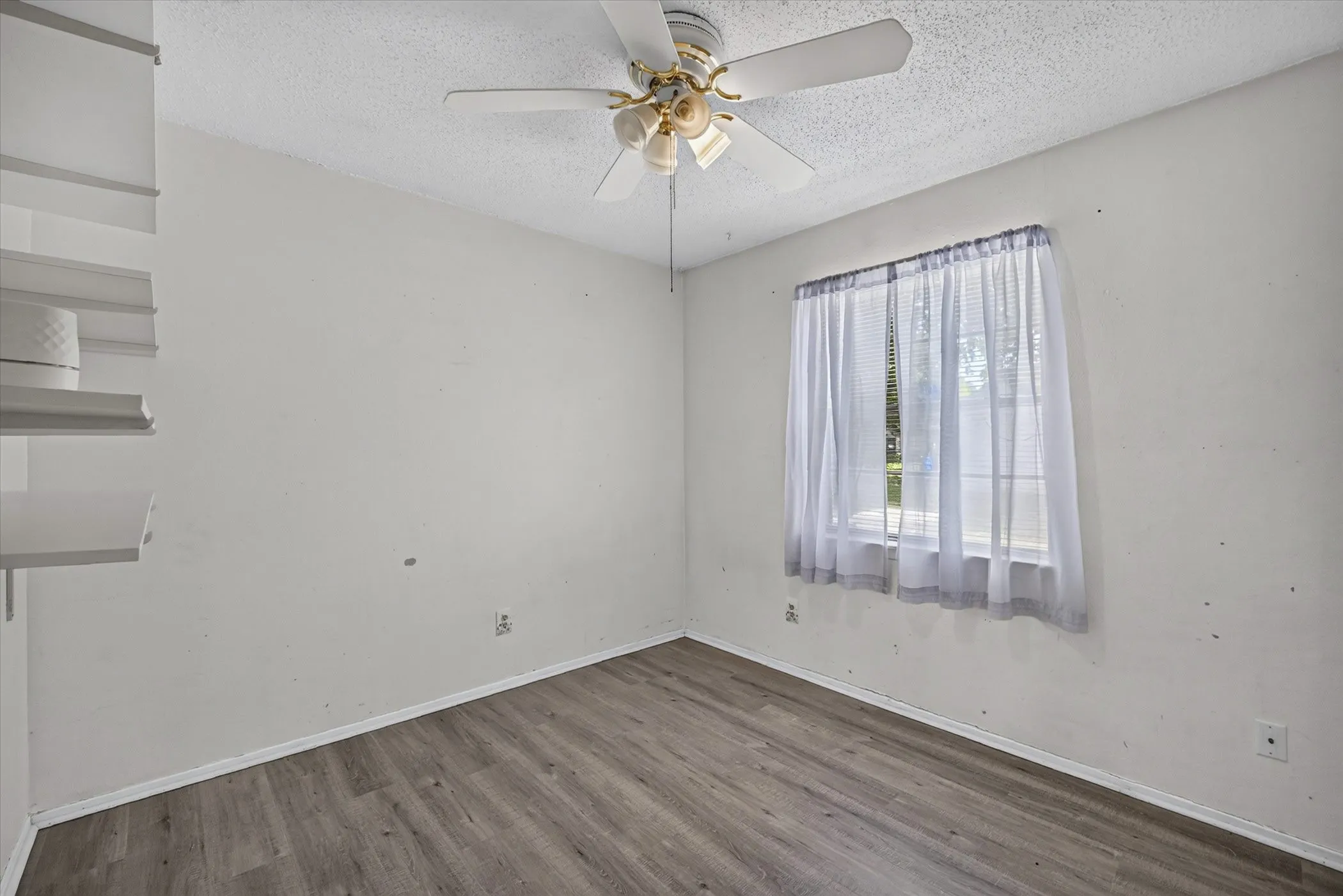 Interior room with wood-finish flooring, white walls, and a ceiling fan with integrated lighting