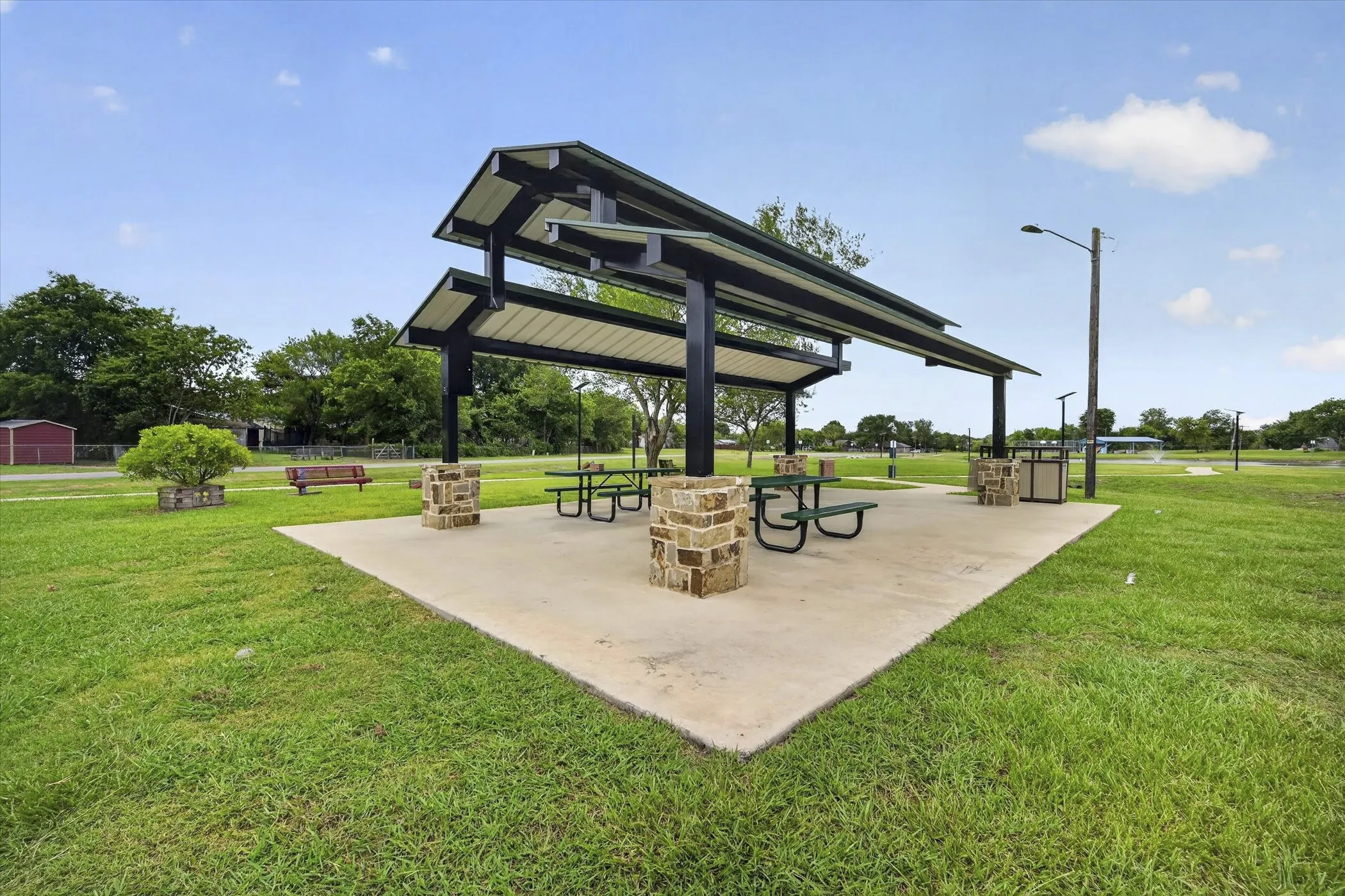Expansive outdoor pavilion with a concrete pad and stone-clad support columns
