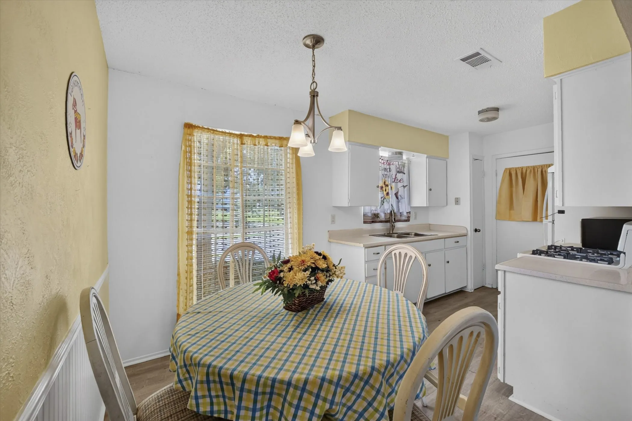 Integrated kitchen and dining area featuring white cabinetry, a double basin sink, and a gas range