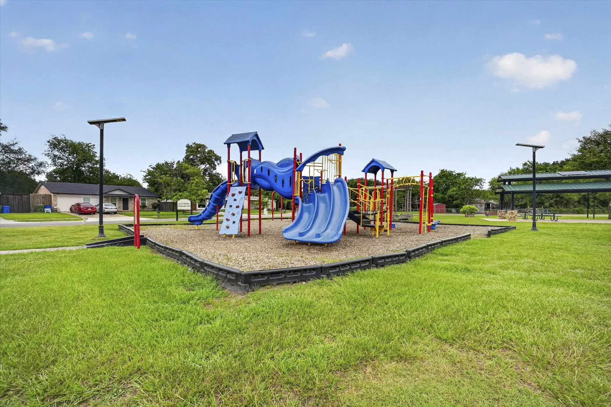 Community playground featuring multiple slides, climbing structures, and protective ground covering