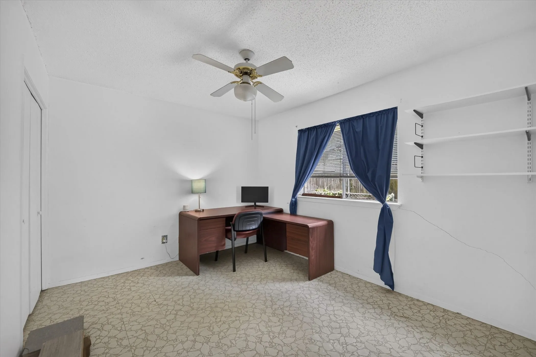 Bright interior space featuring a window, built-in shelving, ceiling fan, and light-toned flooring