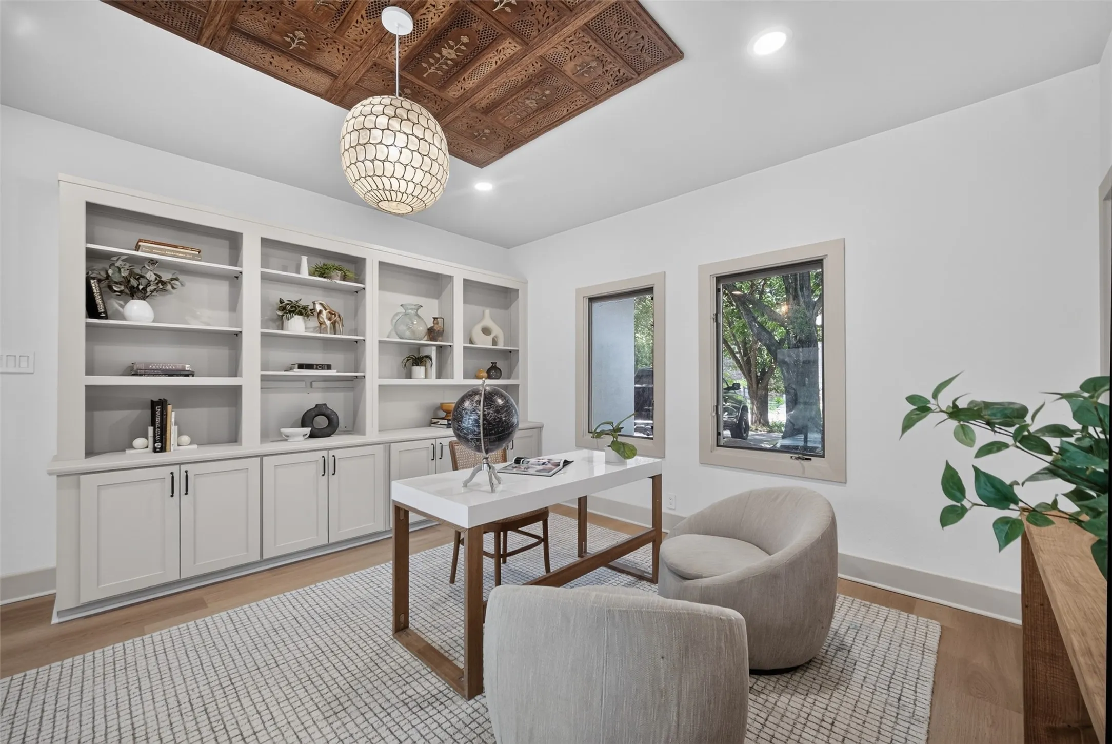 Room featuring a decorative ceiling panel, light wood-finish flooring, and a contemporary pendant light fixture