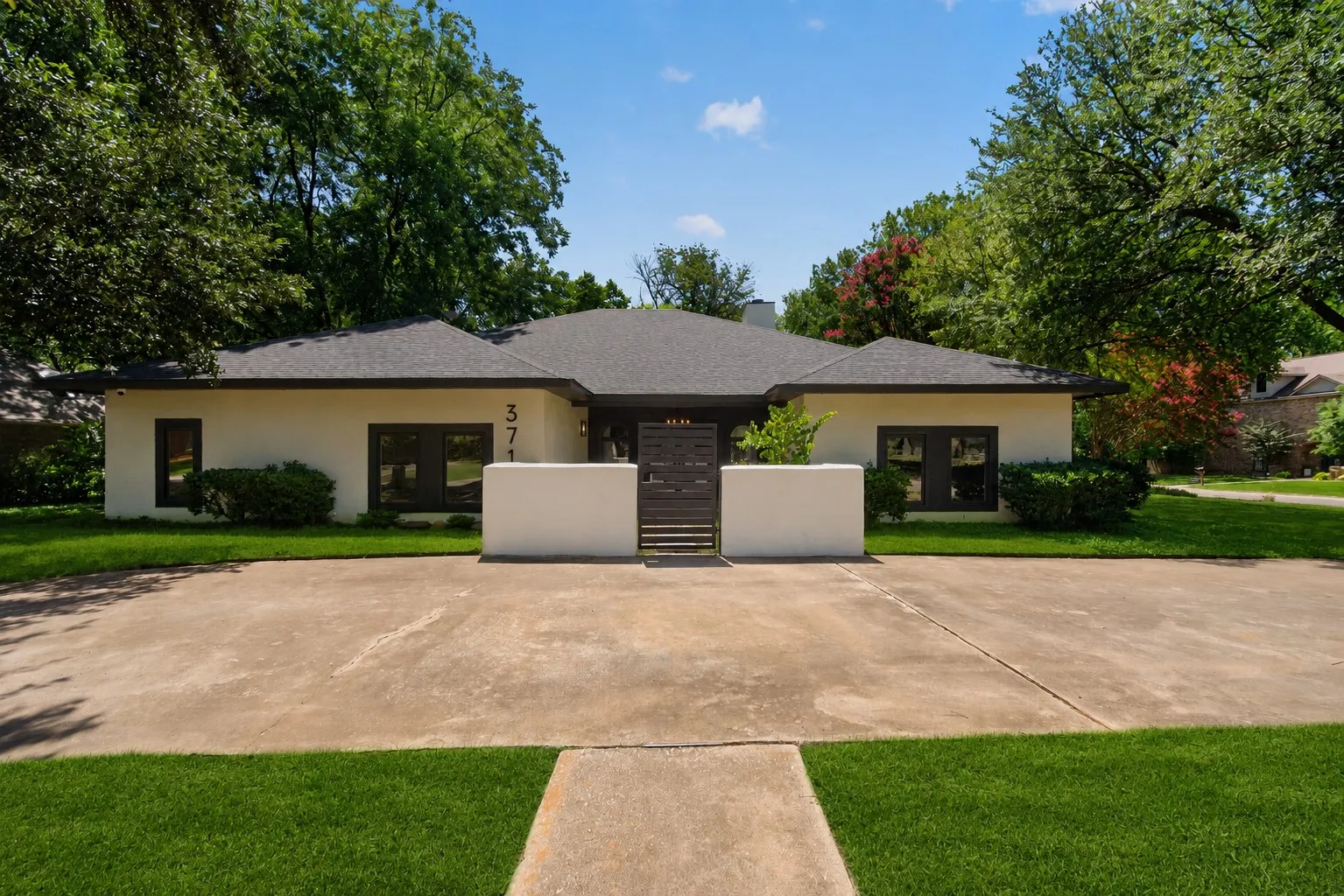 Contemporary single-story residence with a tan stucco exterior and a dark shingle roof