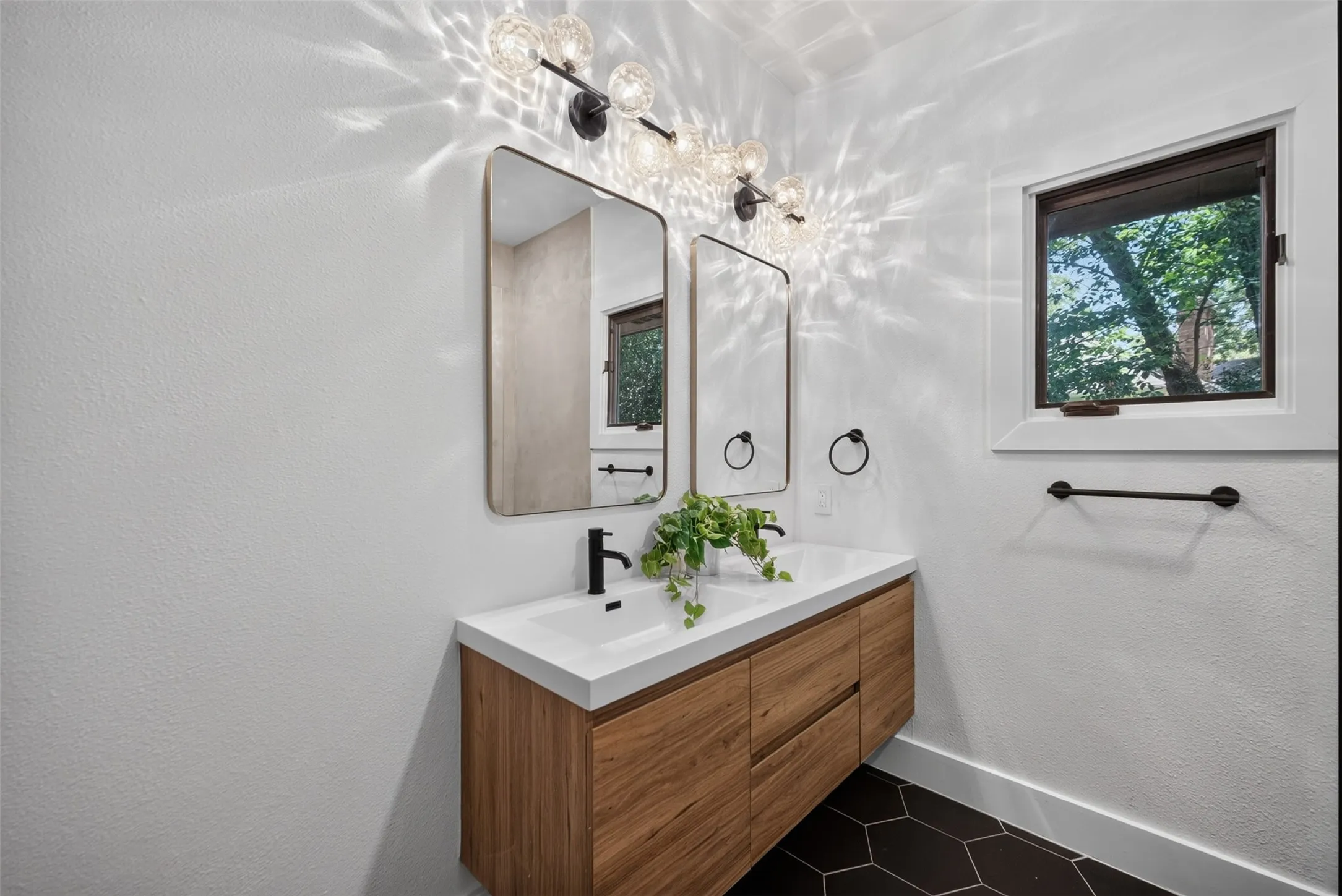Floating wood-finish vanity with an integrated white sink and matte black fixtures