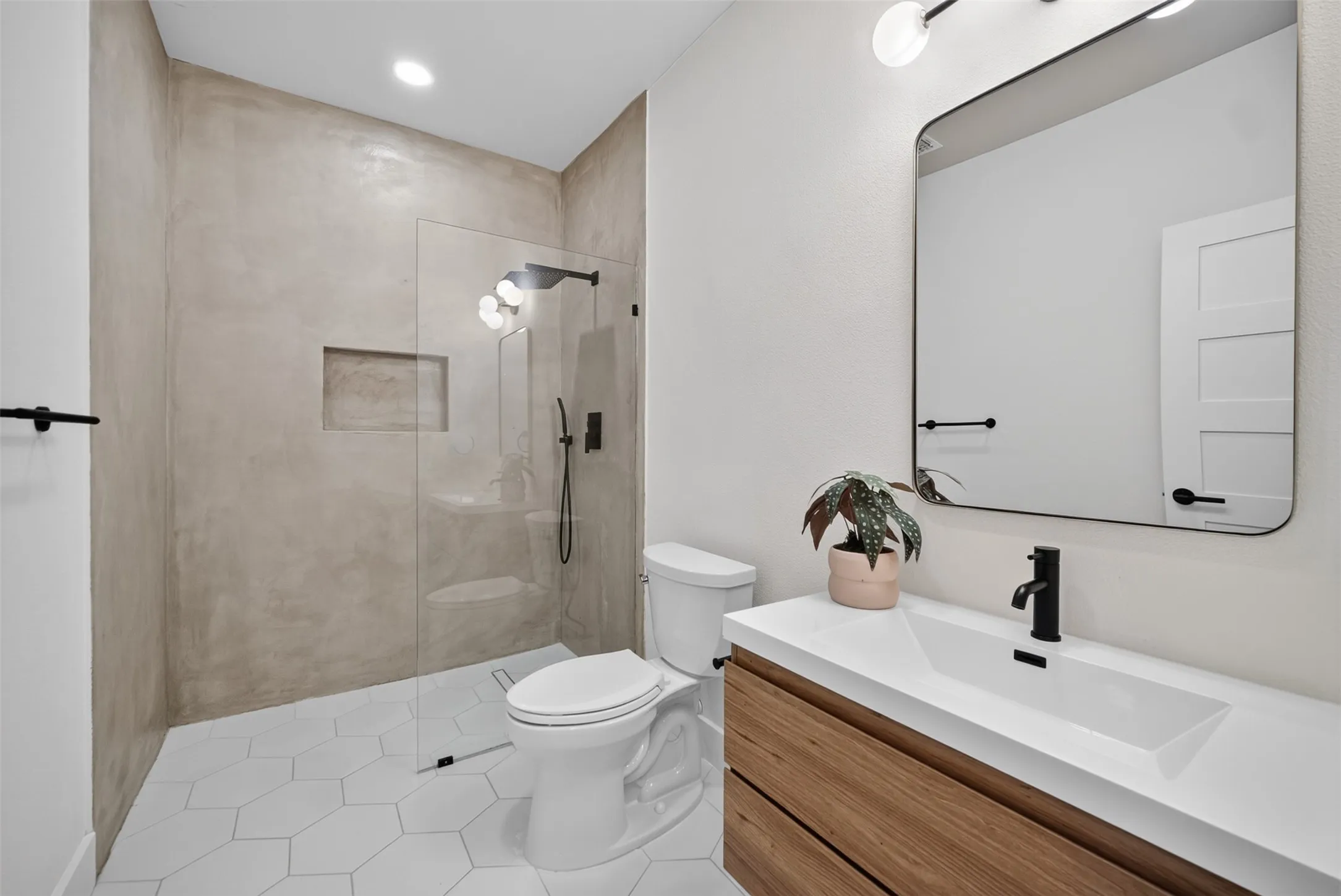 Modern bathroom featuring a wood-finish floating vanity with an integrated sink, a rectangular framed mirror, and matte black fixtures
