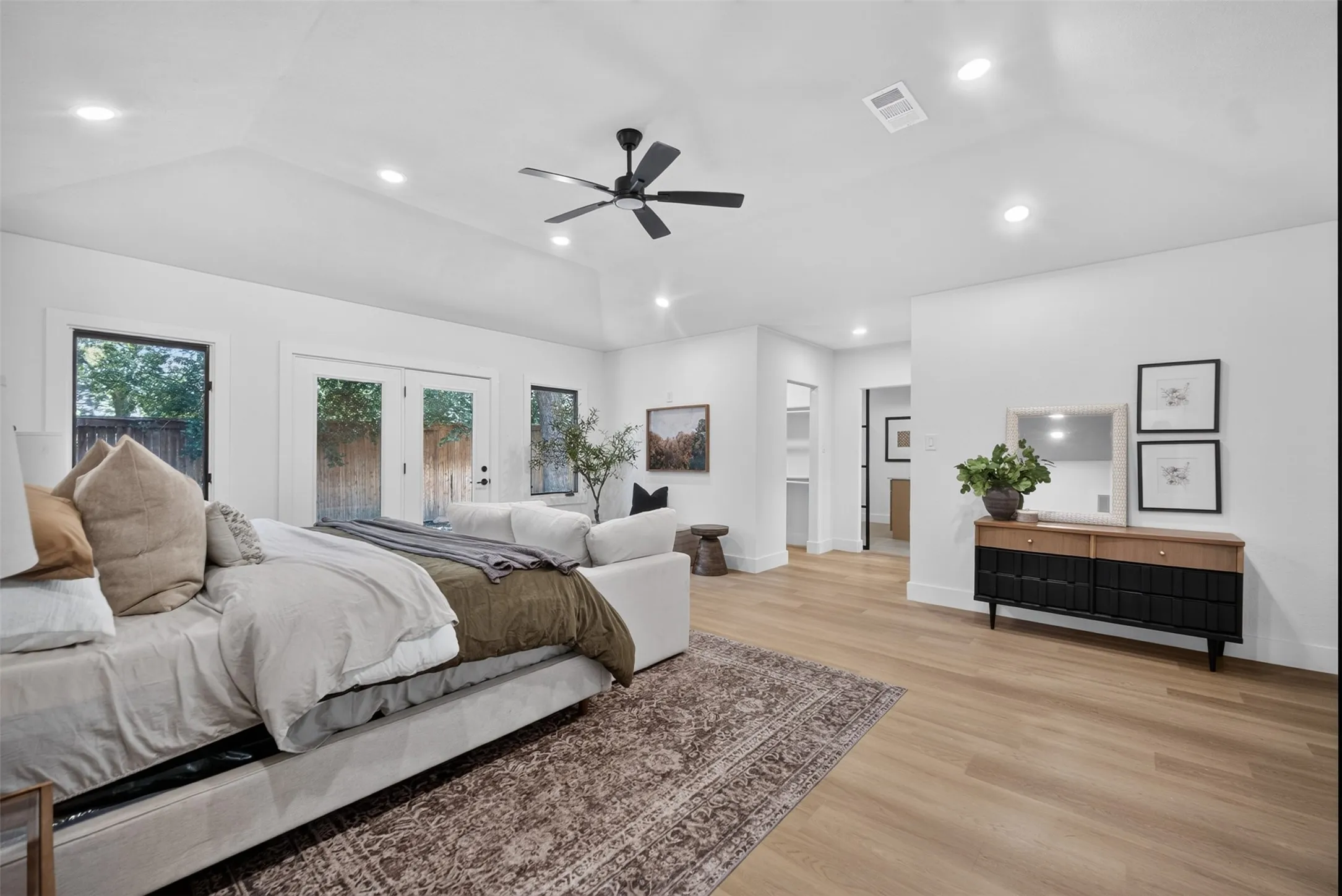 Spacious room with a vaulted ceiling, recessed lighting, and wood-finish flooring
