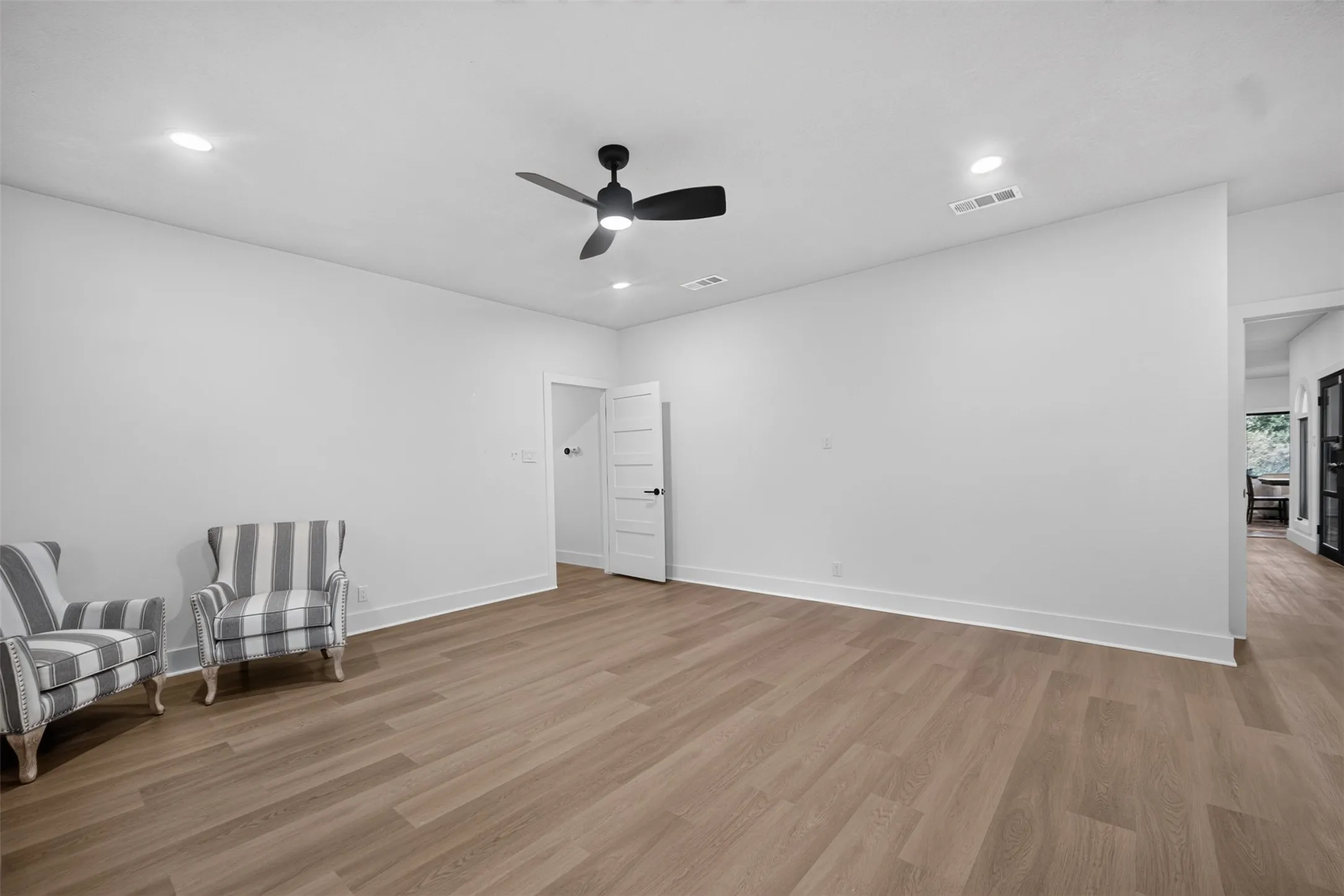 Spacious room featuring wood-finish flooring, recessed lighting, a ceiling fan with integrated lighting, and white baseboards