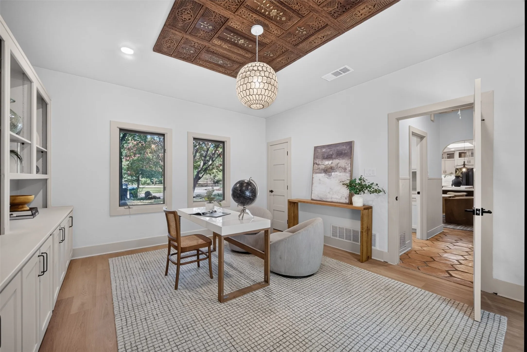 Room featuring a wood ceiling panel with intricate carvings, a decorative chandelier, and light wood-finish flooring