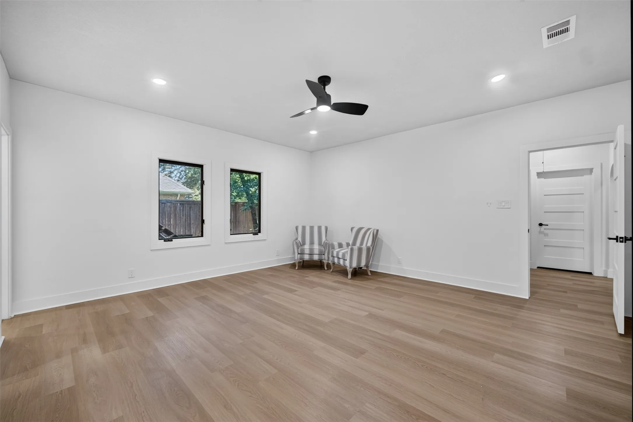 Expansive room featuring wood-finish flooring, recessed lighting, and a contemporary ceiling fan