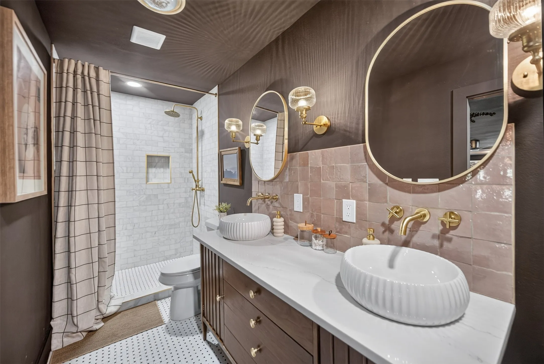 Bathroom featuring a dual vanity with vessel sinks, wall-mounted gold-tone faucets, and rectangular mirrors