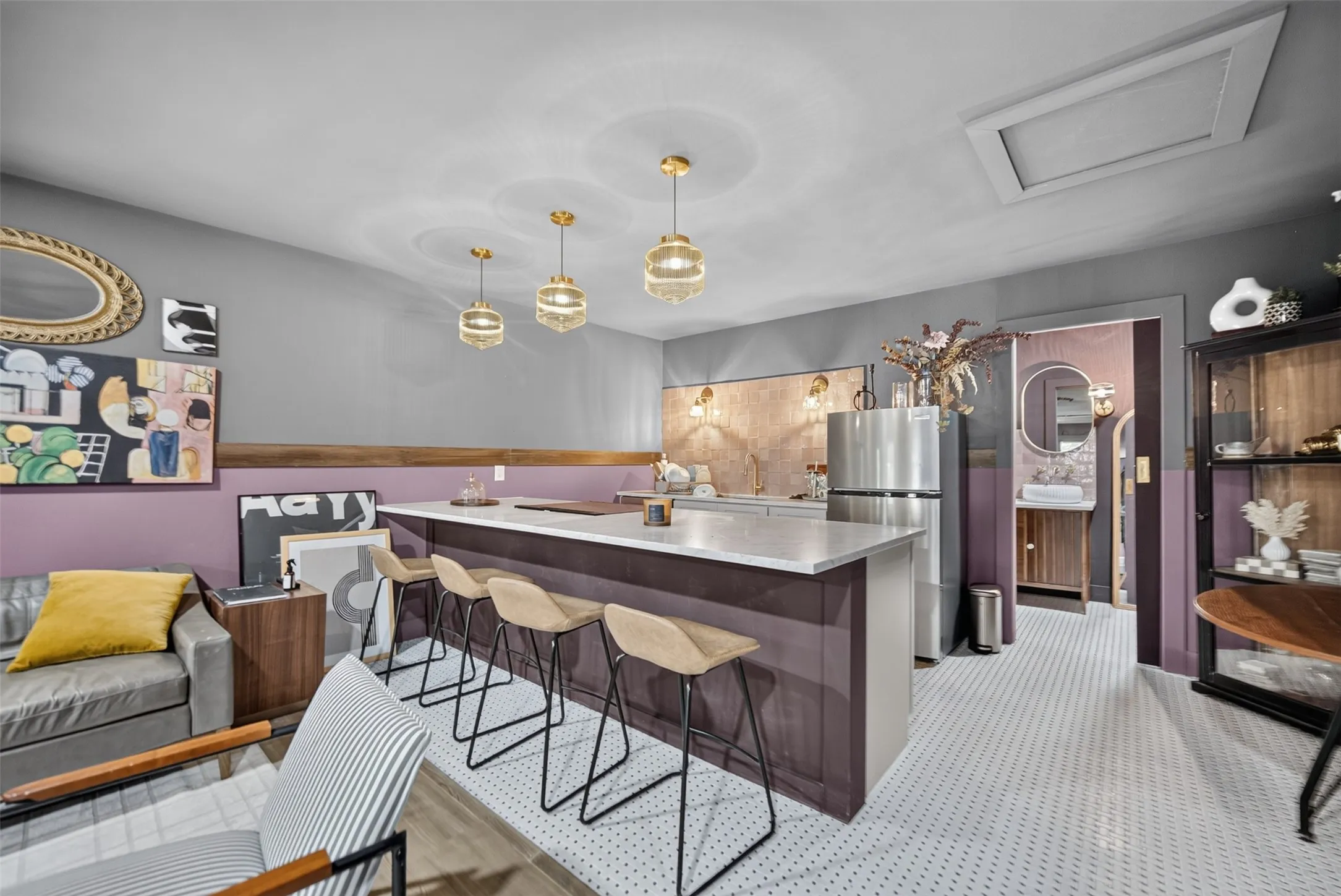 Open-concept kitchen and living area featuring a central island with a light-toned countertop, stainless steel refrigerator, and recessed lighting