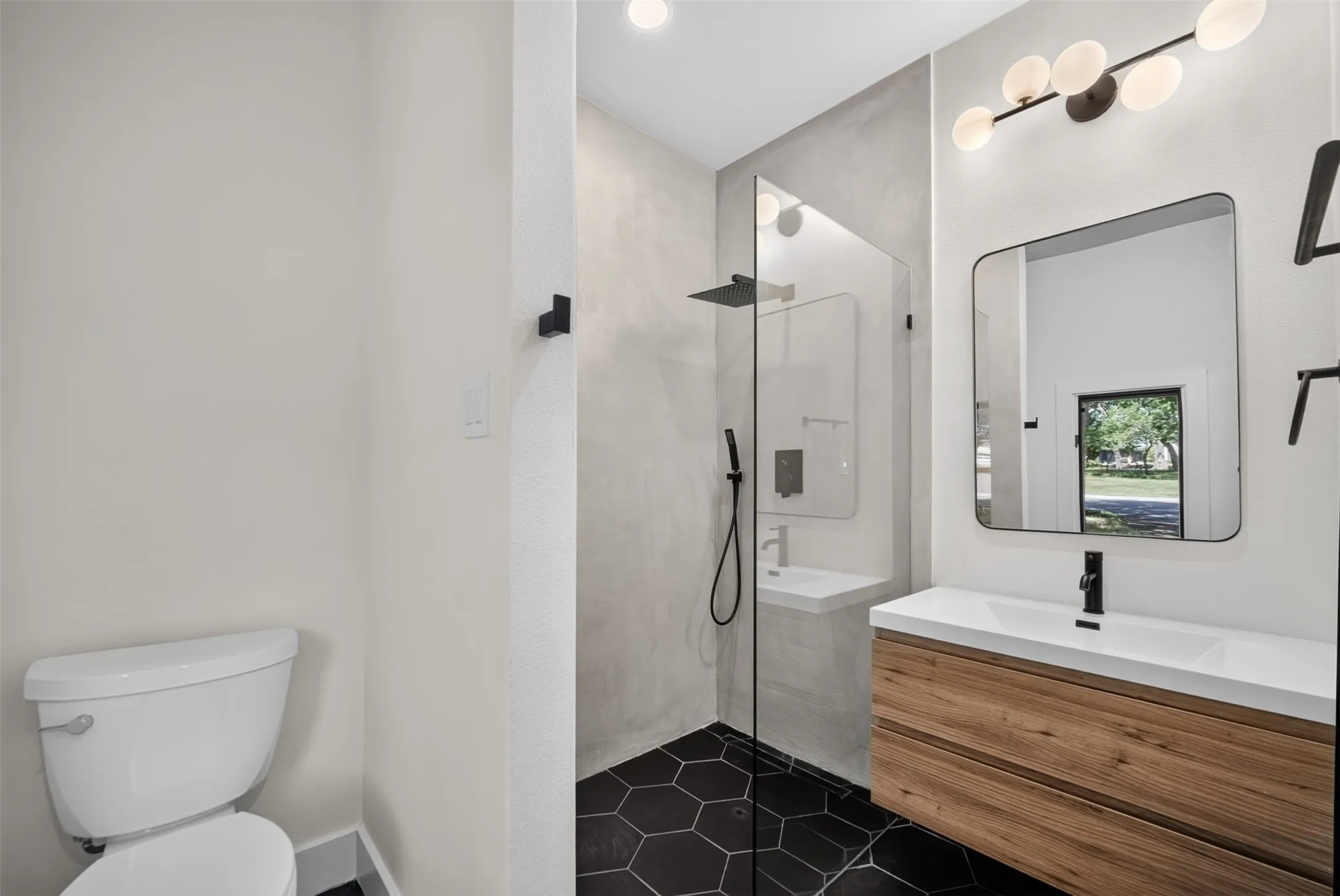 Contemporary bathroom featuring a floating wood-finish vanity with an integrated sink, a rectangular framed mirror, and a wall-mounted light fixture
