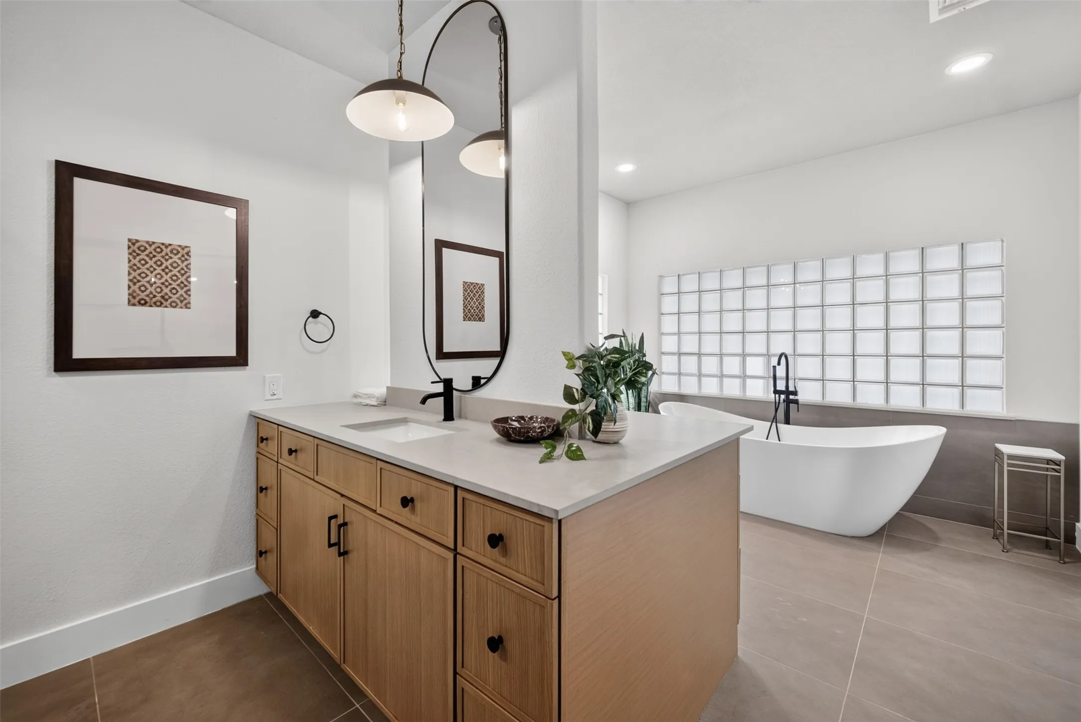 Spacious bathroom featuring a light wood-finish vanity with ample storage, a white countertop, and a sleek undermount sink