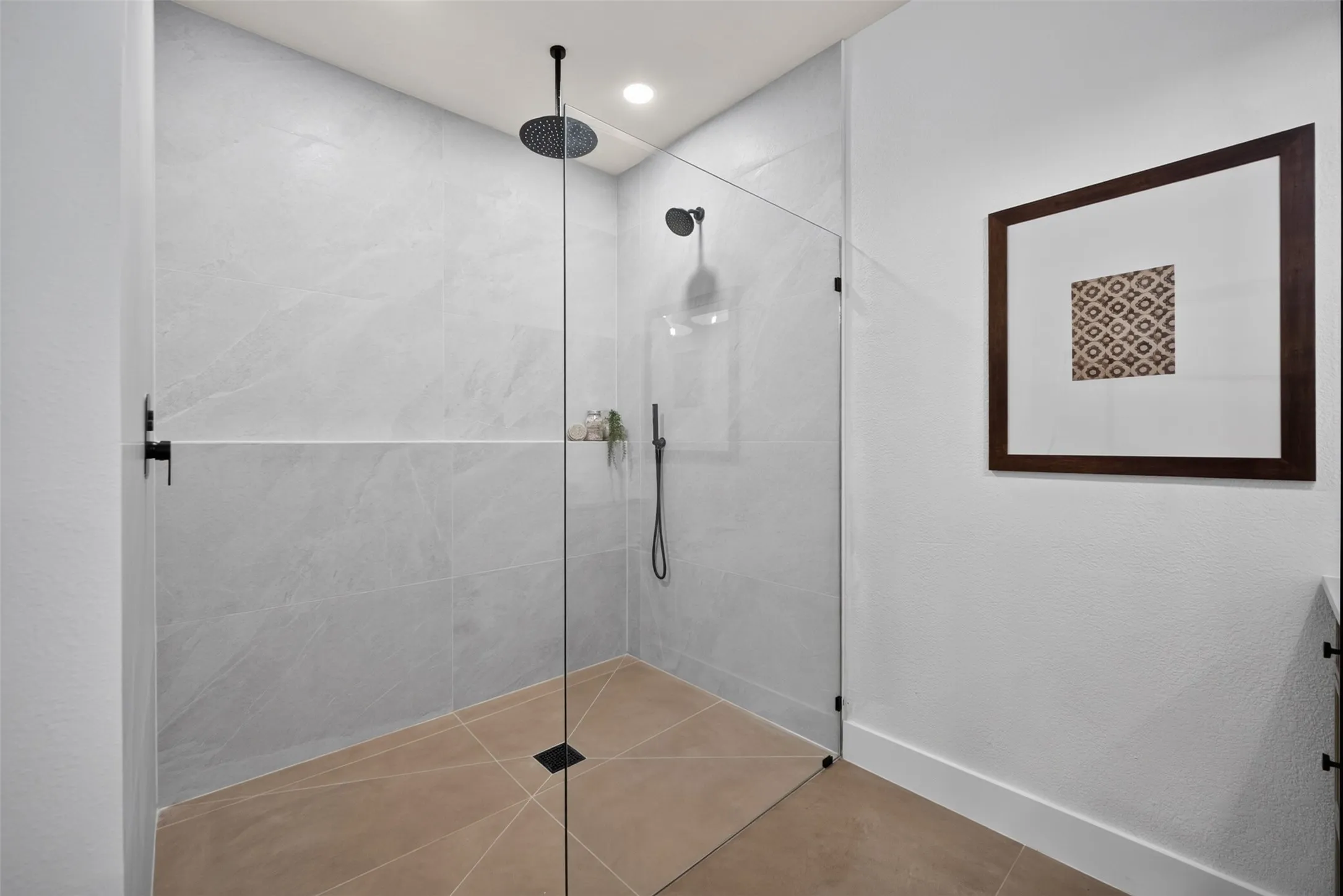 Walk-in shower featuring light grey large-format wall tiles and a contrasting floor tile