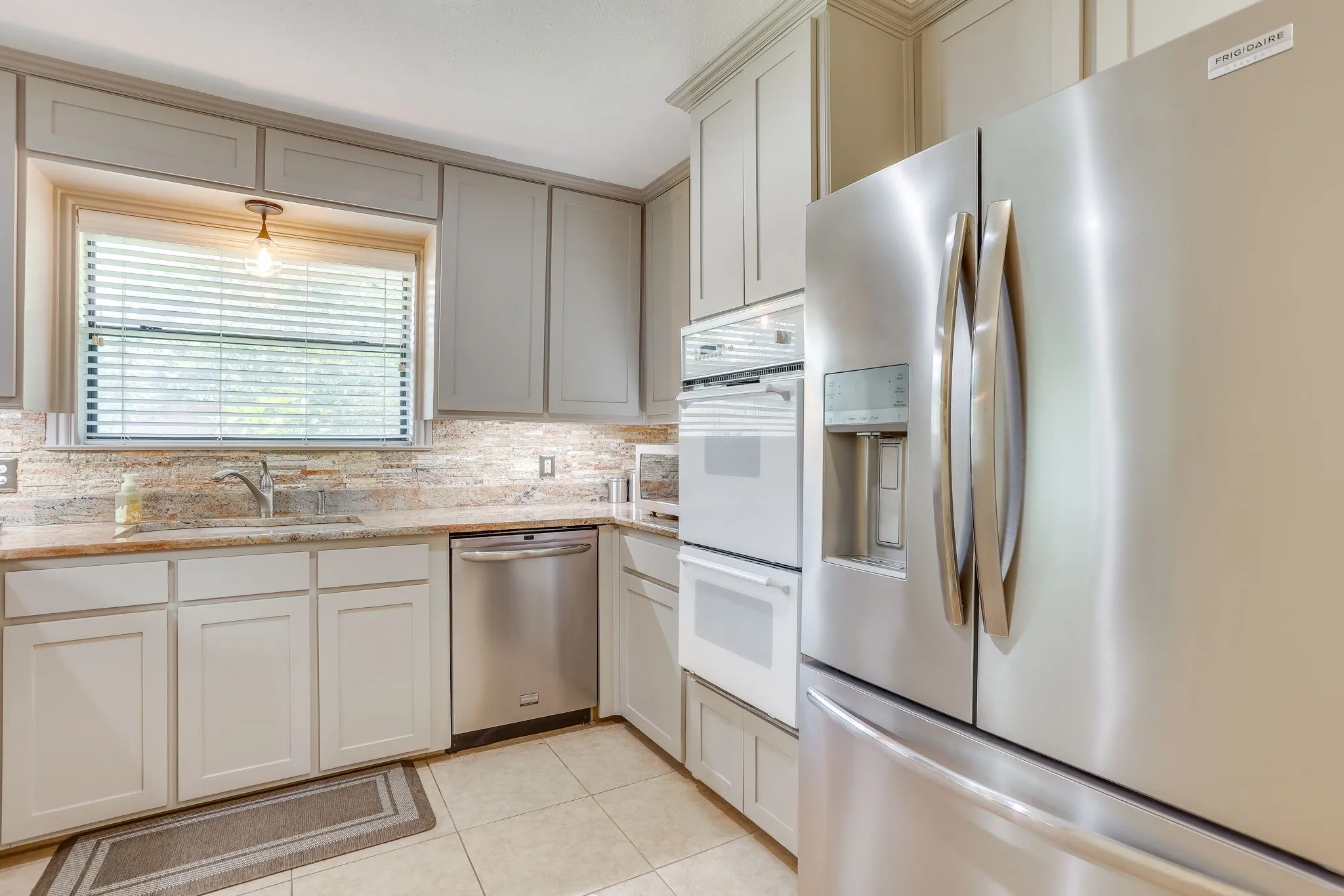 Remodeled kitchen with new cabinets, granite counter tops, stacked stone backsplash, new dishwasher and undermounted cabinet lighting