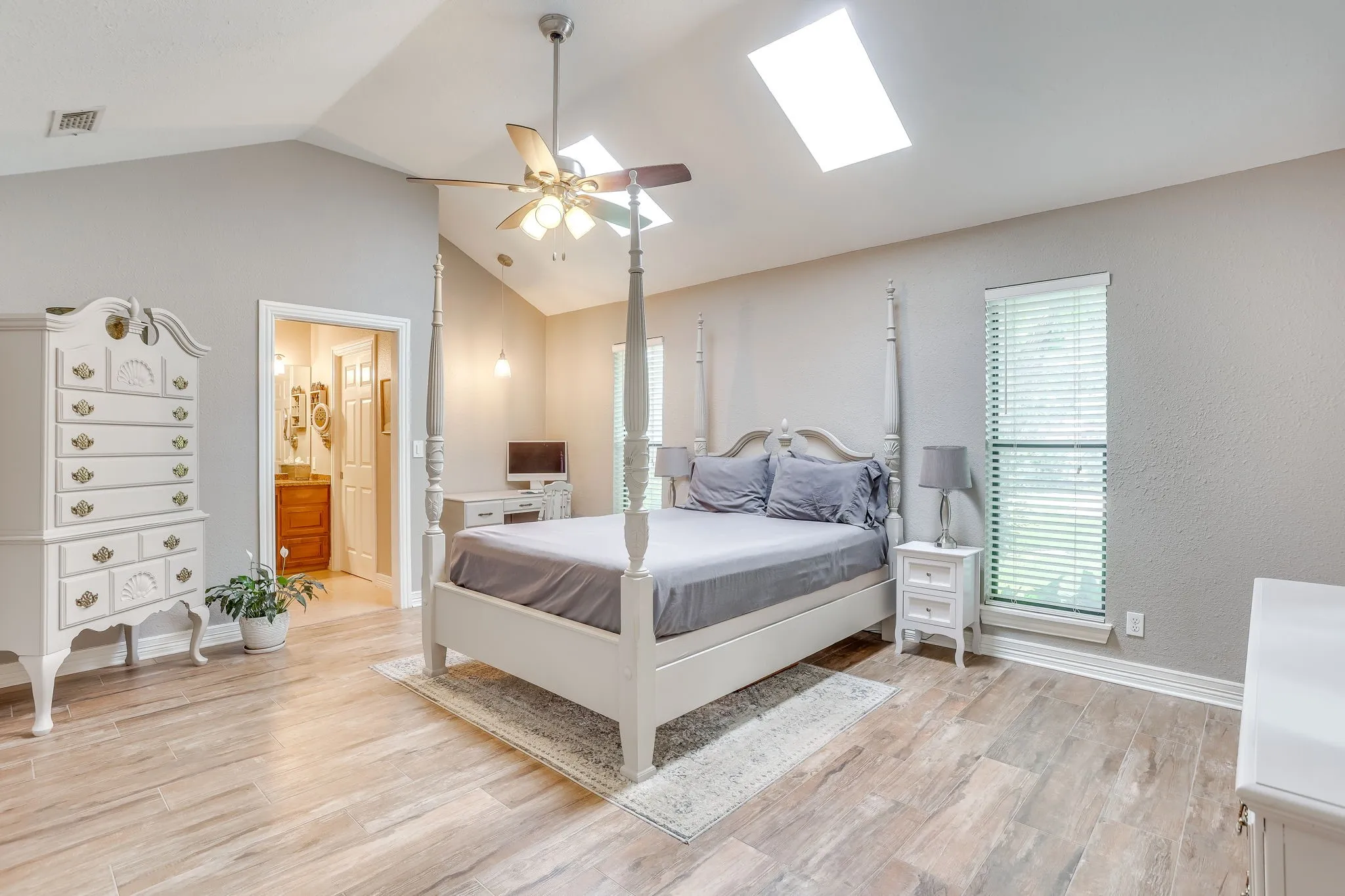 Huge primary bedroom with skylights and a vaulted ceiling