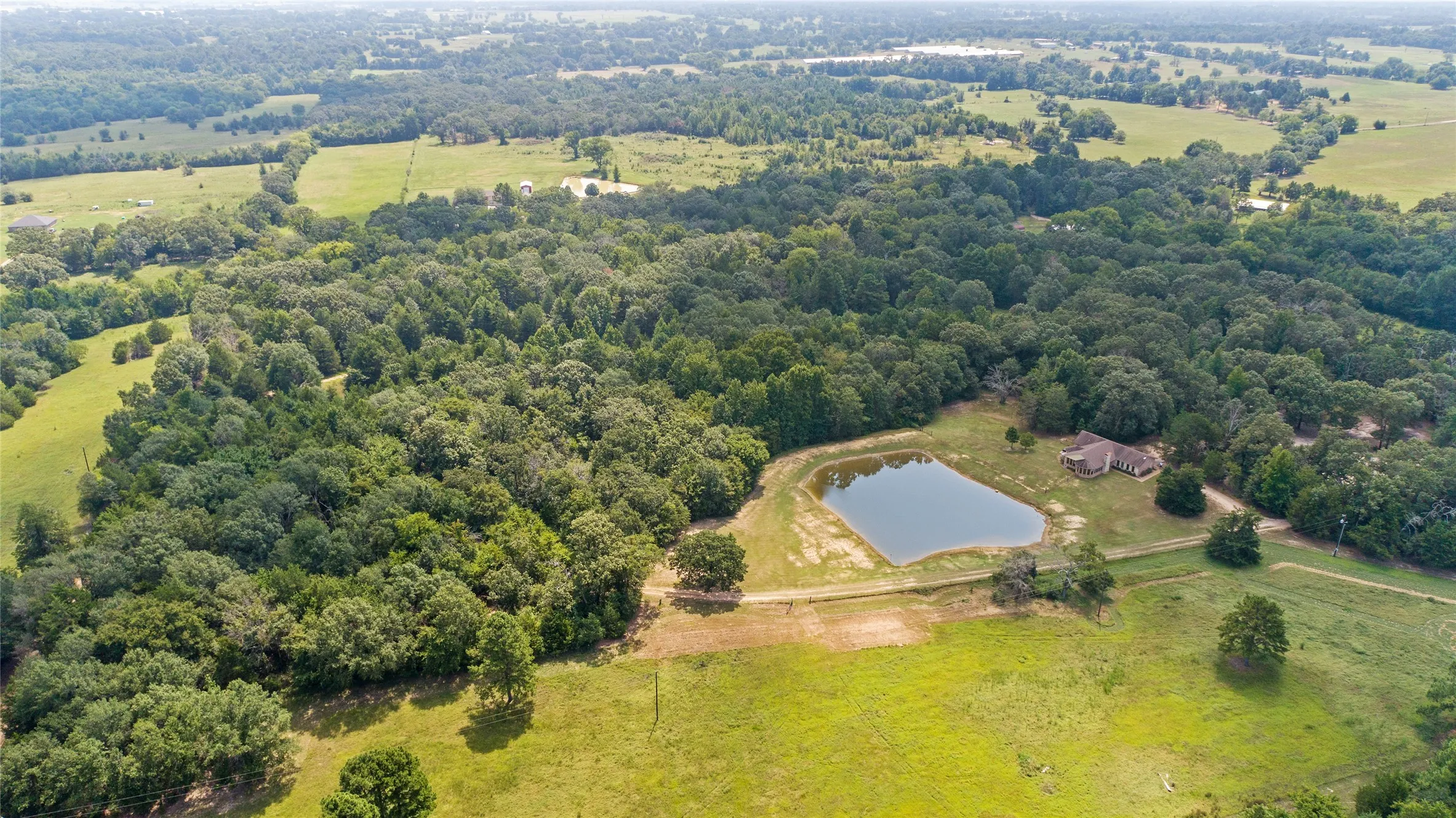 Drone aerial view of a scenic 24.8 acre country estate and private pond in Winnsboro Texas.