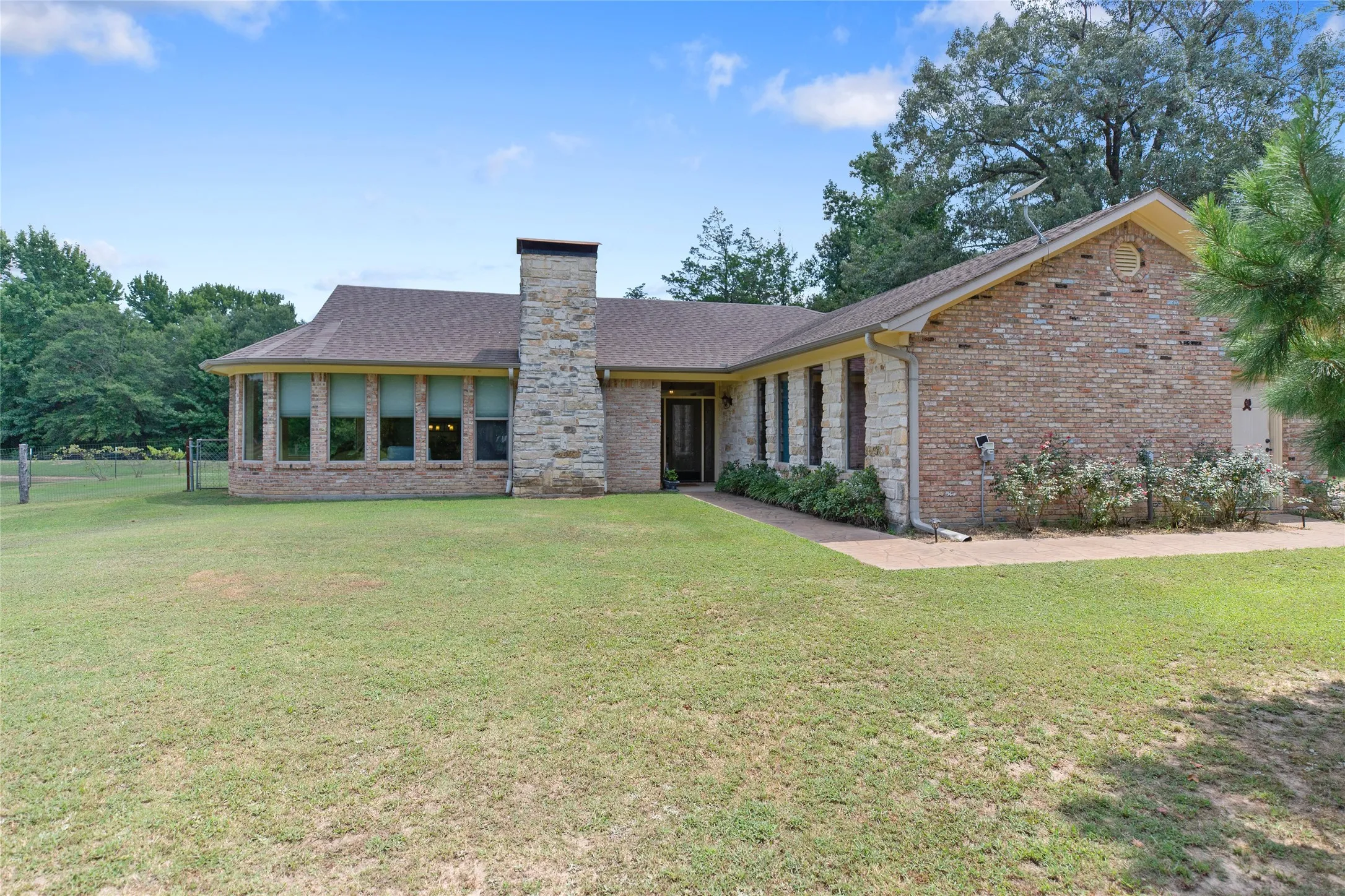 Front view of a custom brick home on a 24.8 acre Winnsboro East Texas estate with a manicured front yard.
