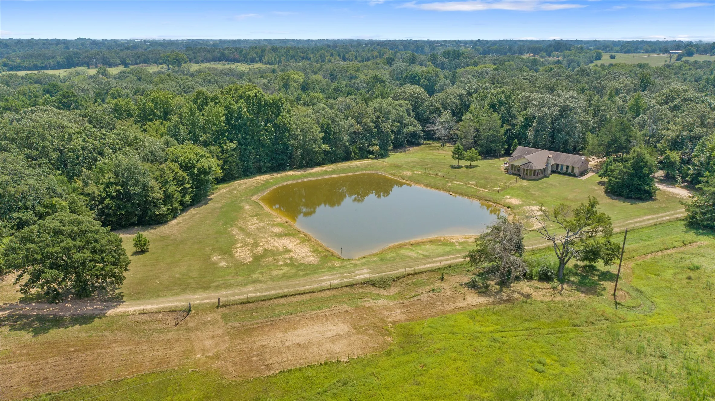 Aerial drone shot of the entire 24.8 acre ranchette showcasing the pond and green pastures.