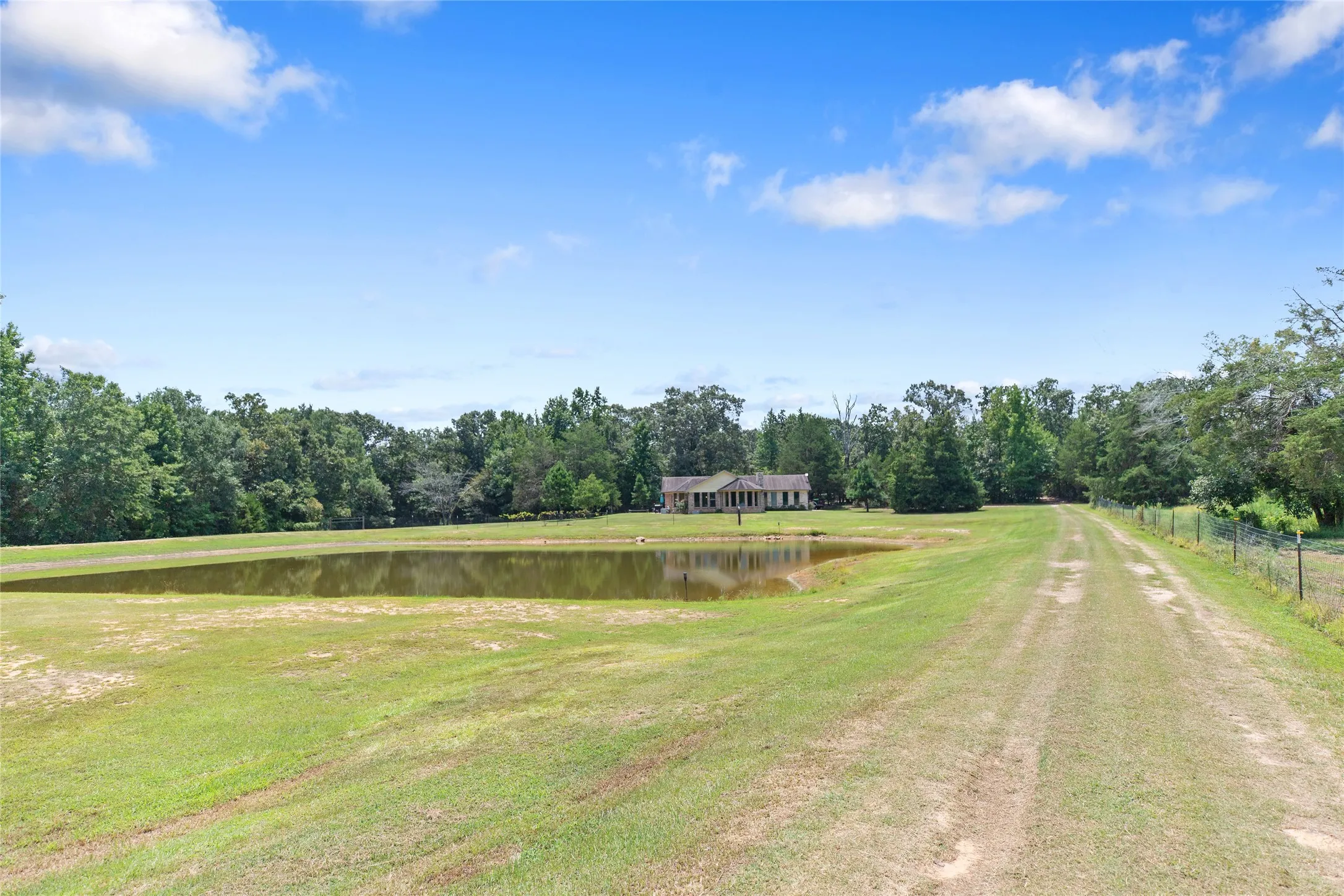Scenic property view highlighting the transition from open fields to the private stock pond.