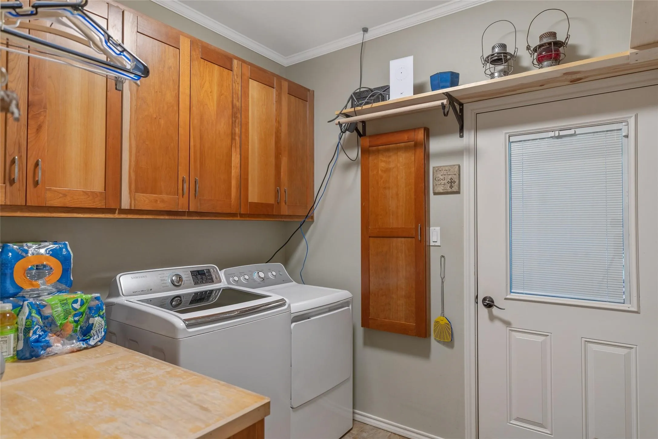 Dedicated laundry room washroom featuring custom wood cabinetry and overhead storage space.