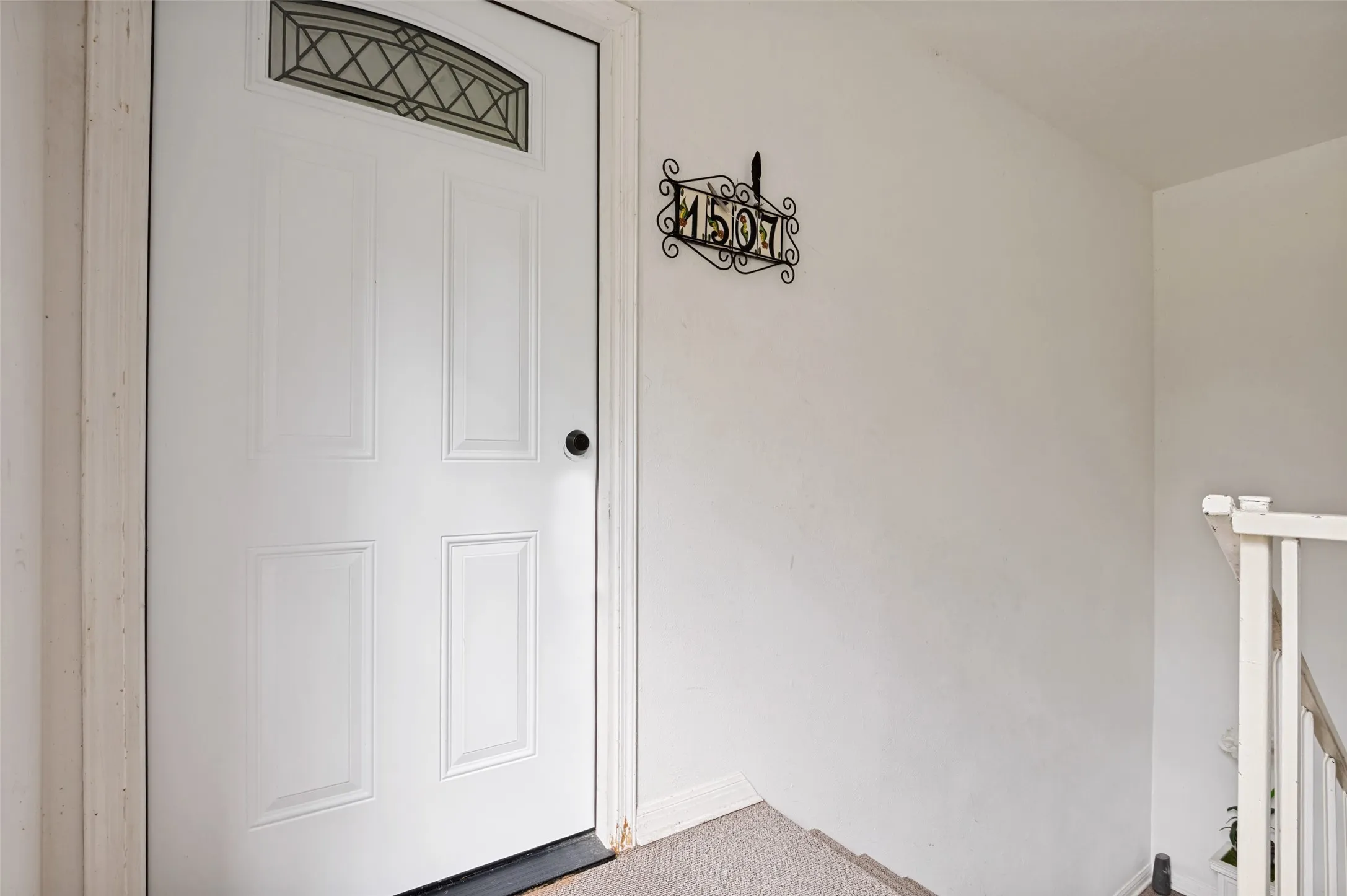 White paneled door featuring an arched leaded glass transom