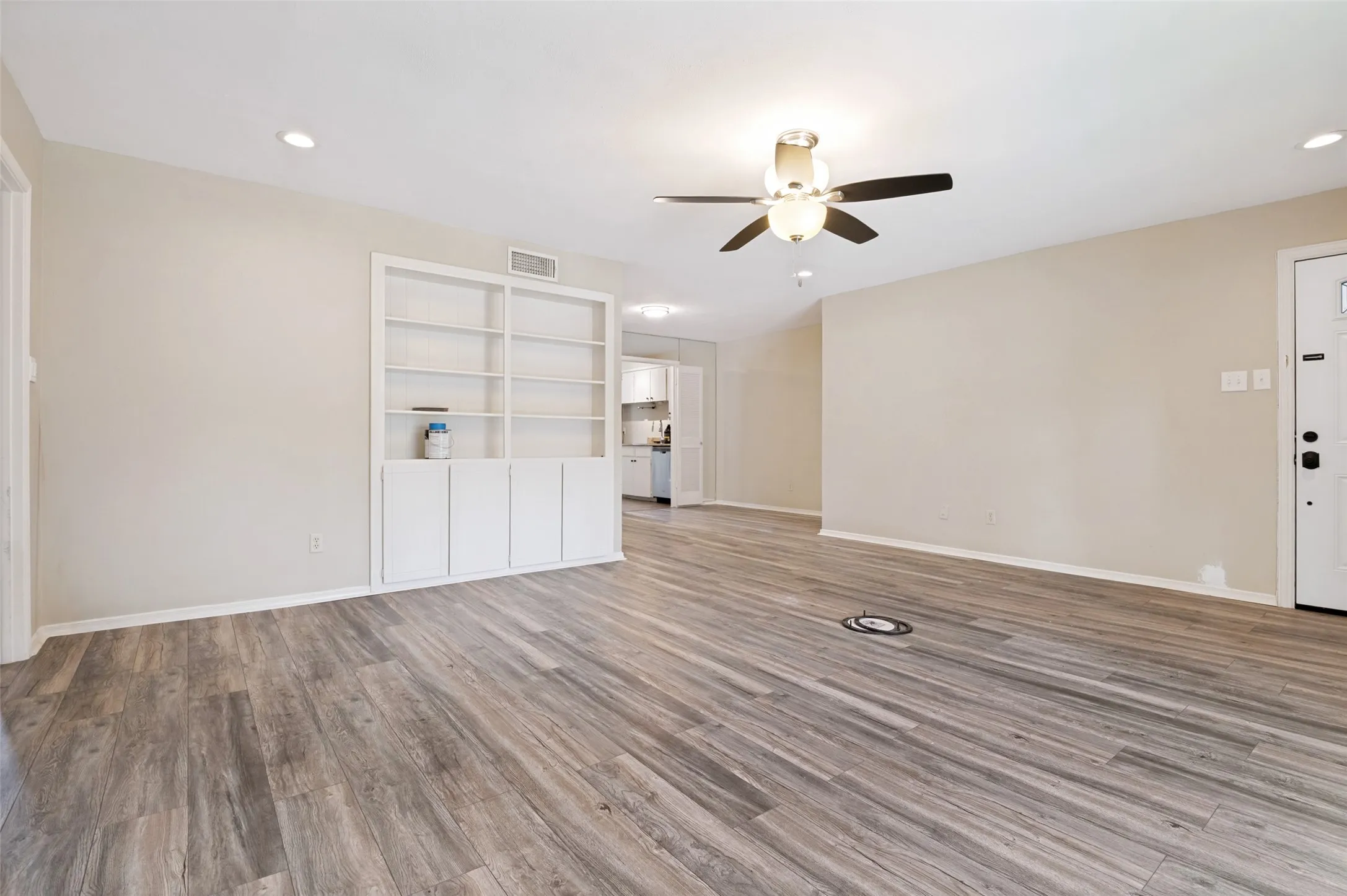 Spacious room featuring wood-finish flooring, recessed lighting, and a ceiling fan