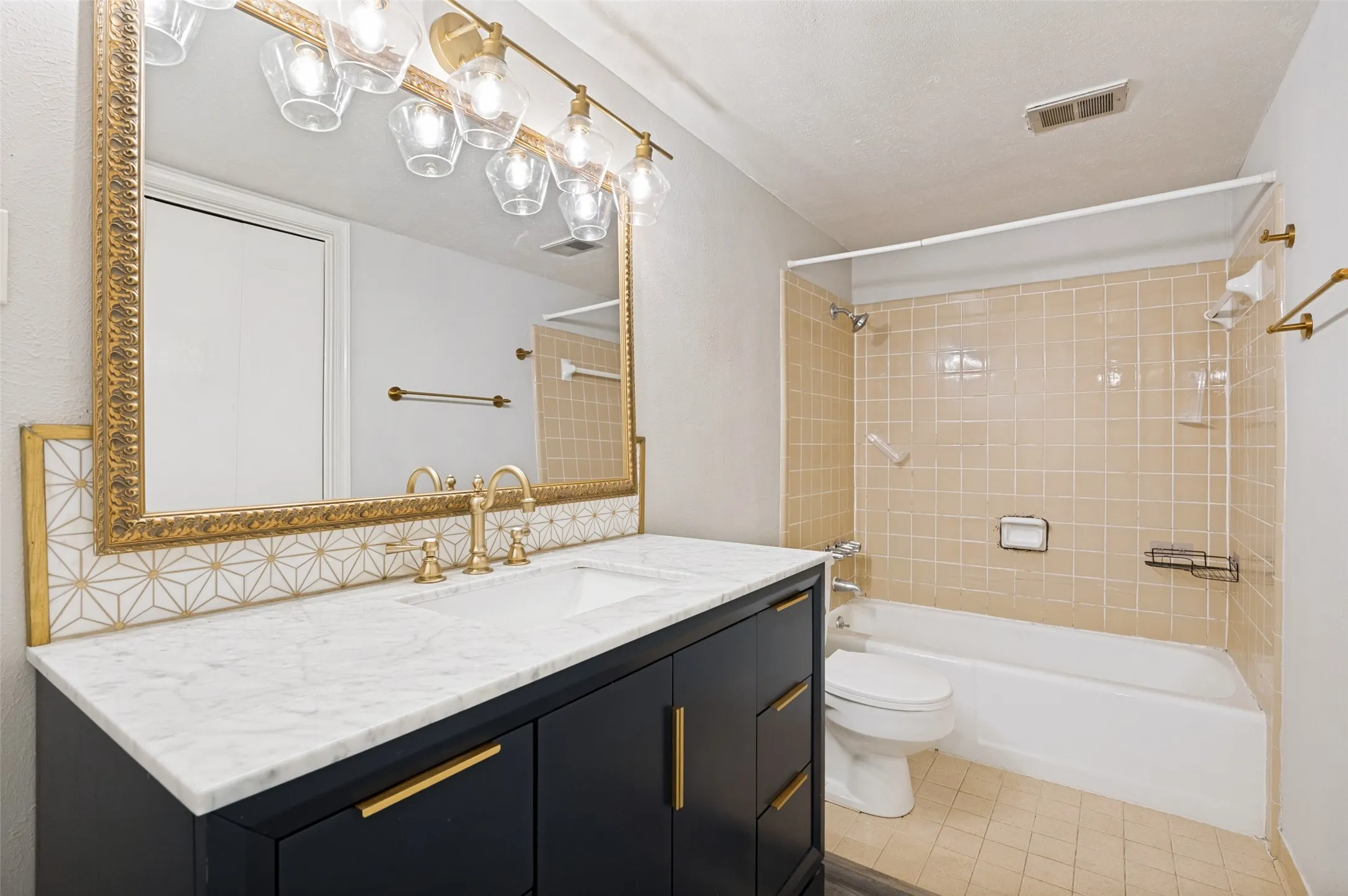 Bathroom featuring a dark vanity with gold hardware, a white countertop, and a built-in sink