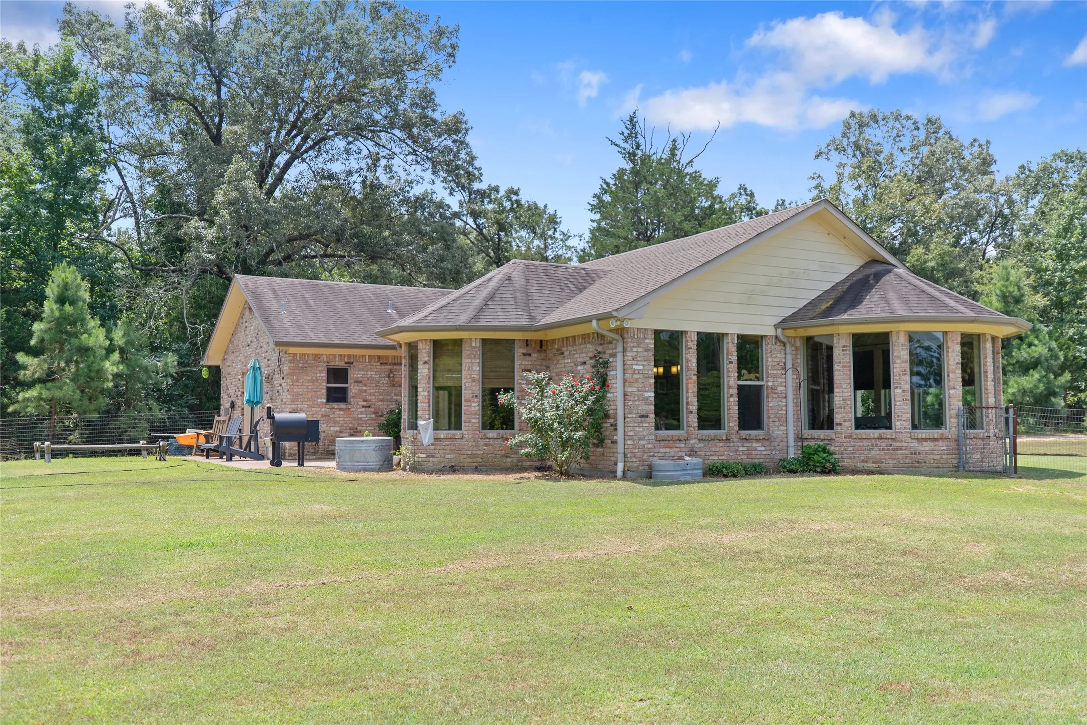 Rear view of the custom brick home showing the back patio and open yard space.