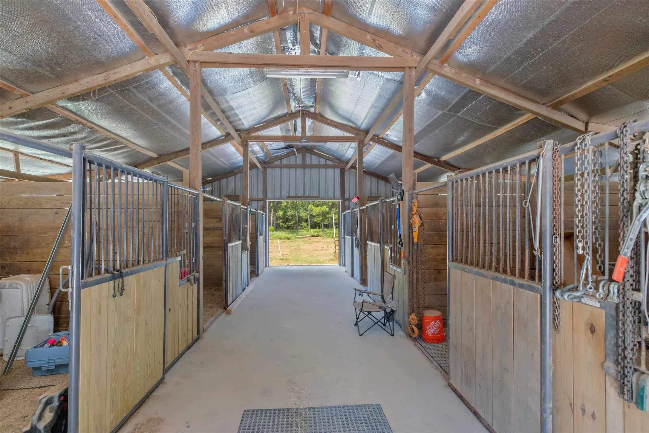 Interior view of the pristine six stall barn featuring a wide center aisle and concrete flooring.