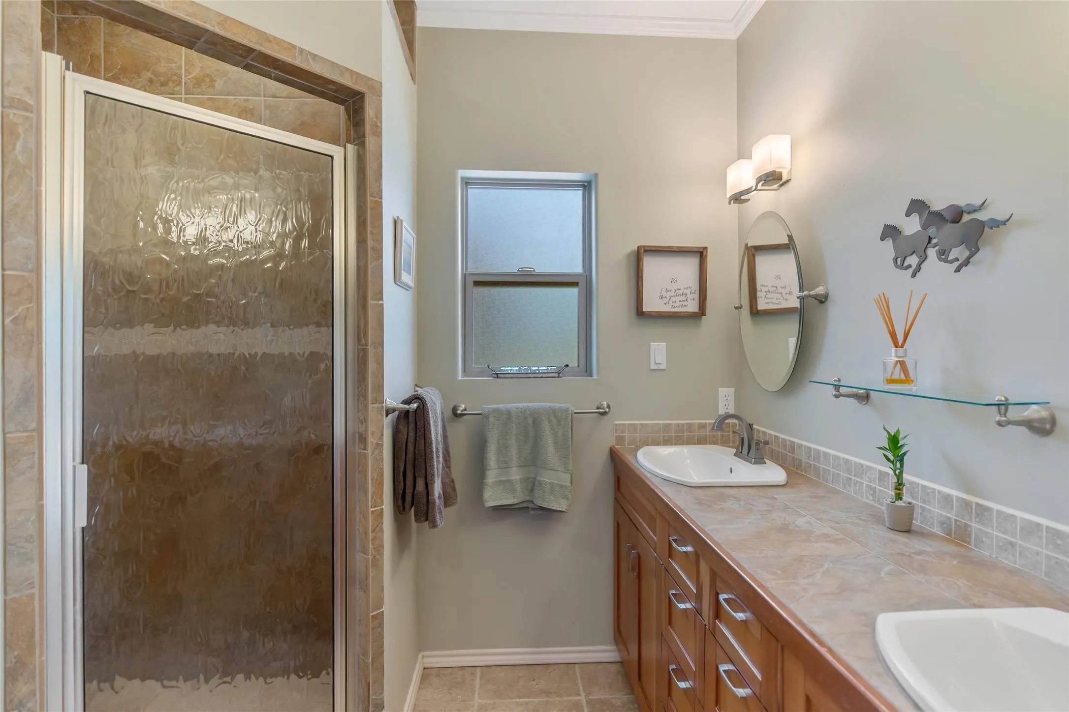 Full primary bathroom featuring double vanities, updated fixtures, and a walk in shower.