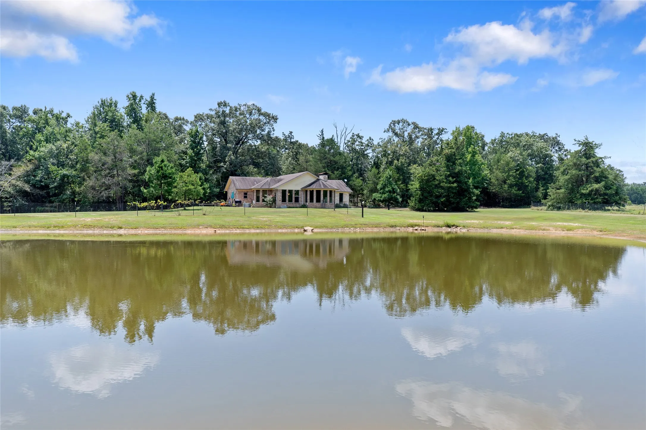 Scenic water view capturing the reflection of the home and blue sky in the private pond.