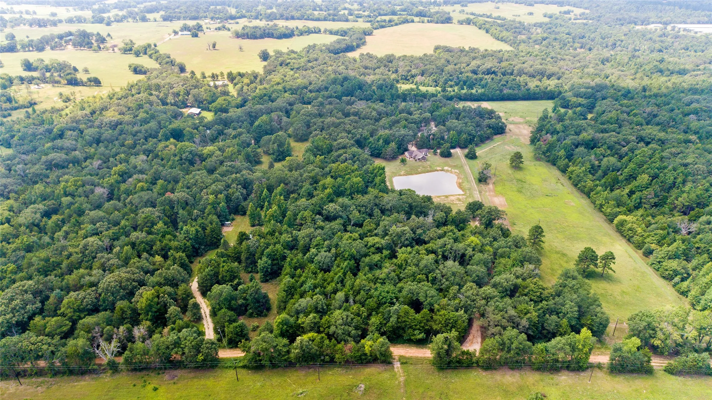 High altitude drone shot of expansive green pastures and mature woods in Wood County Texas.