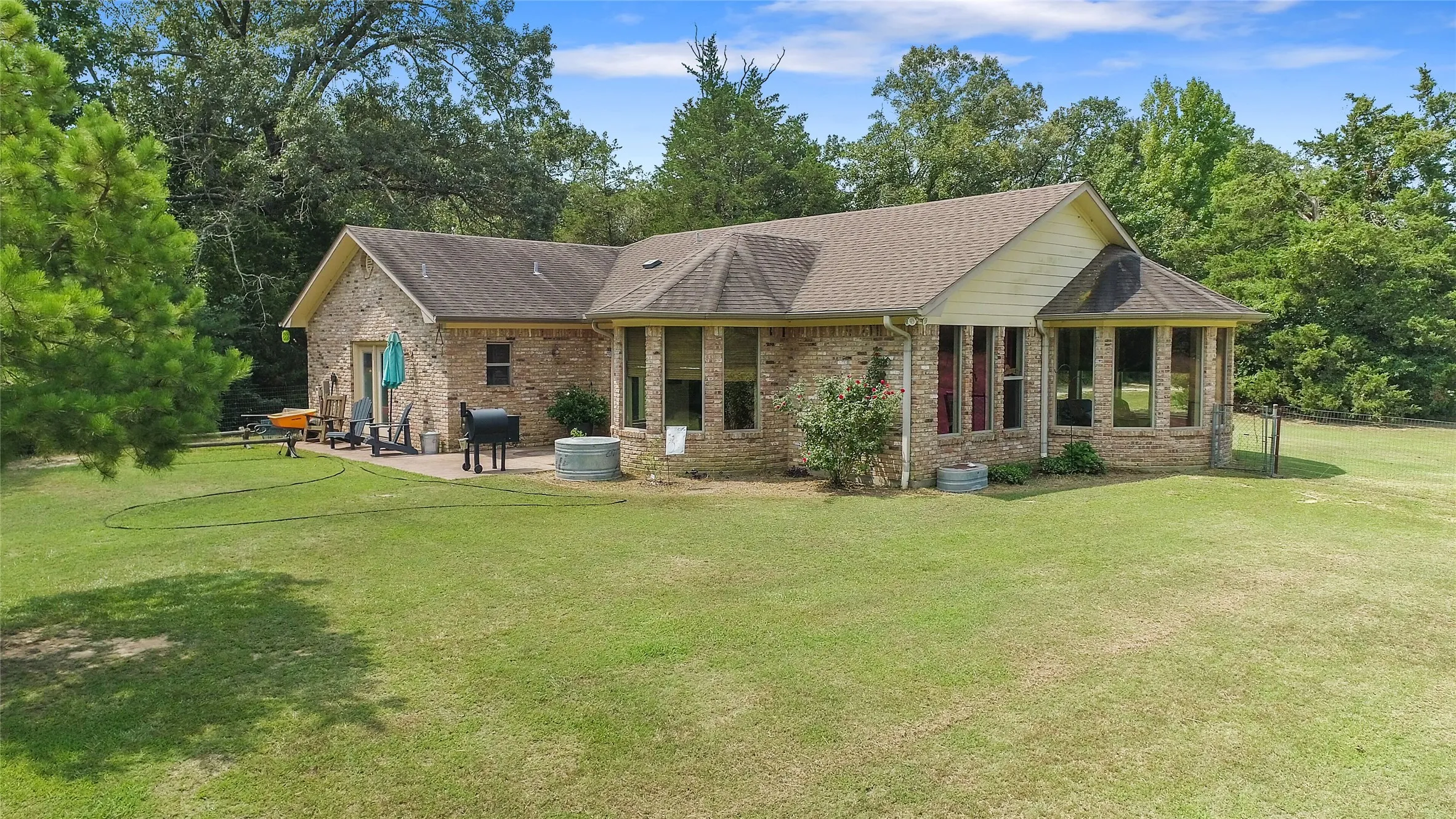 Rear view of custom brick home showing the spacious backyard and acreage in East Texas.