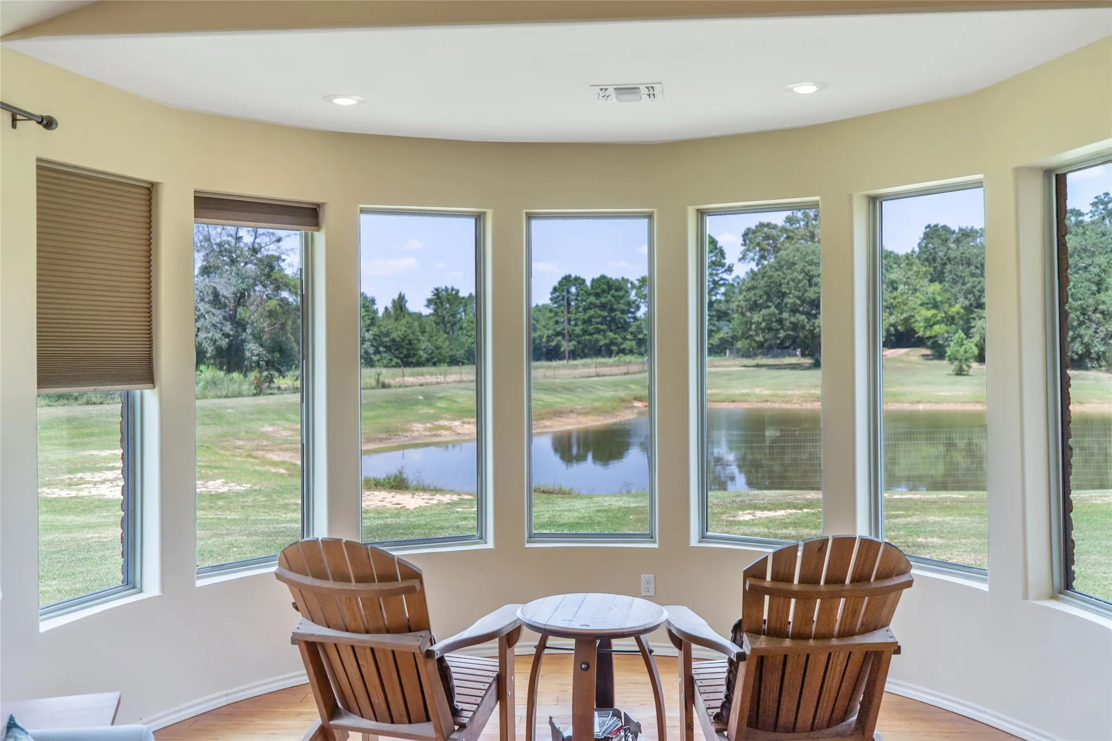 Bright sunroom with beautiful wood finished ceilings and panoramic window views of the pond and acreage.