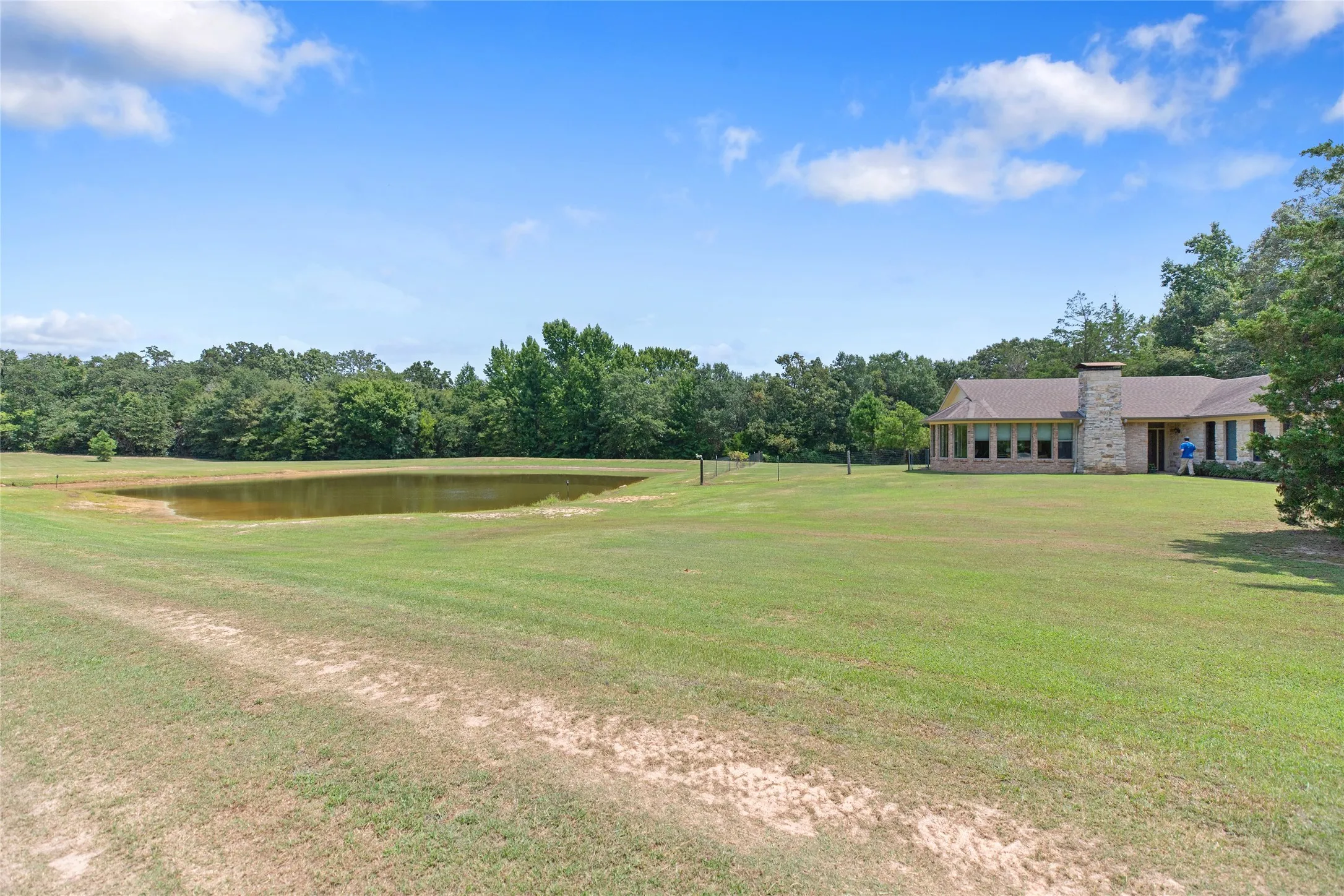 Wide angle view of the expansive green acreage, pastures, and home exterior.