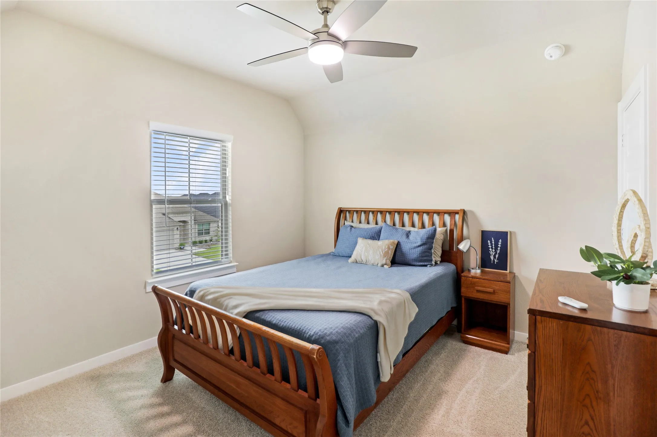 Carpeted bedroom featuring a ceiling fan with integrated lighting, a window with horizontal blinds, and neutral wall tones