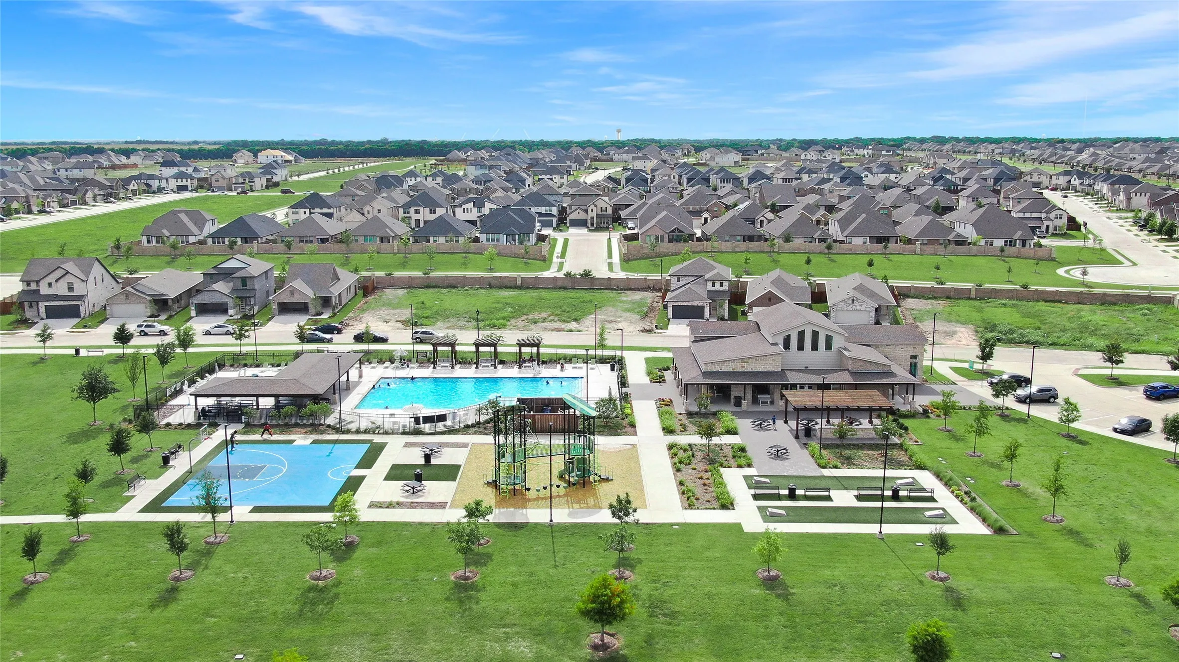 Community clubhouse and amenity center featuring a swimming pool, basketball court, and green spaces