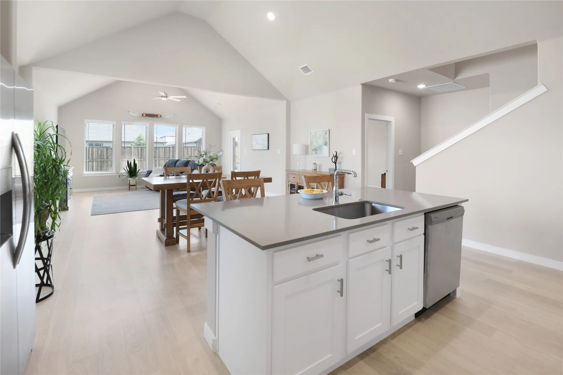 Central kitchen island featuring a stainless steel sink, ample cabinetry, and a built-in dishwasher