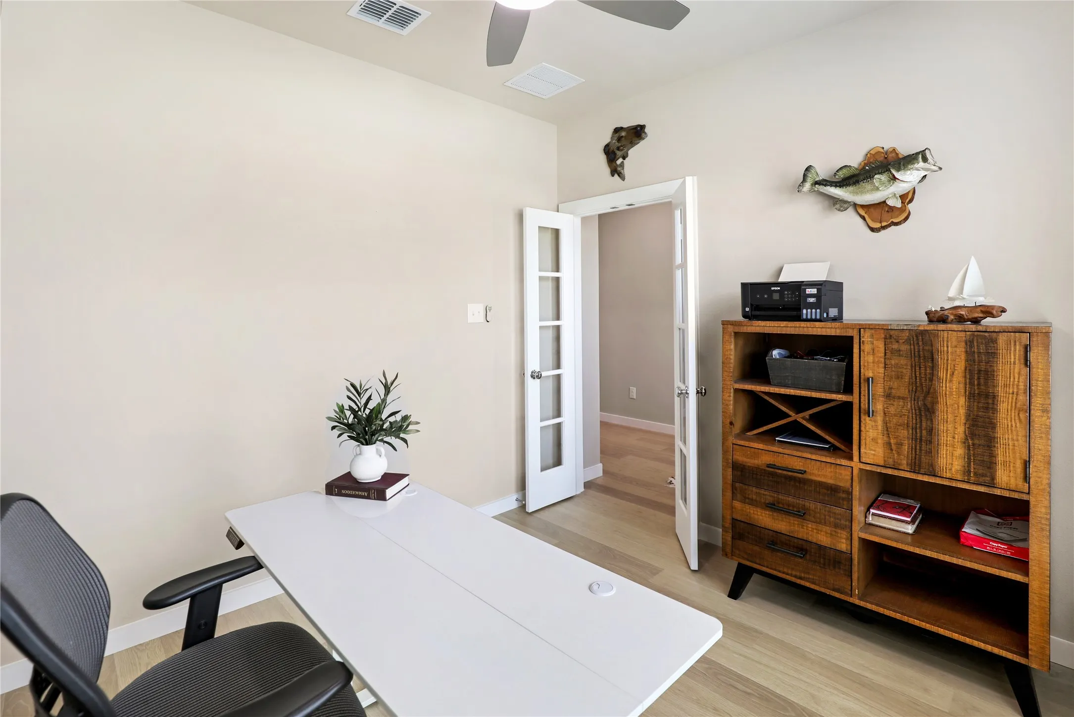 Room featuring light-toned walls, wood-finish flooring, a ceiling fan, and double French doors with frosted glass panels