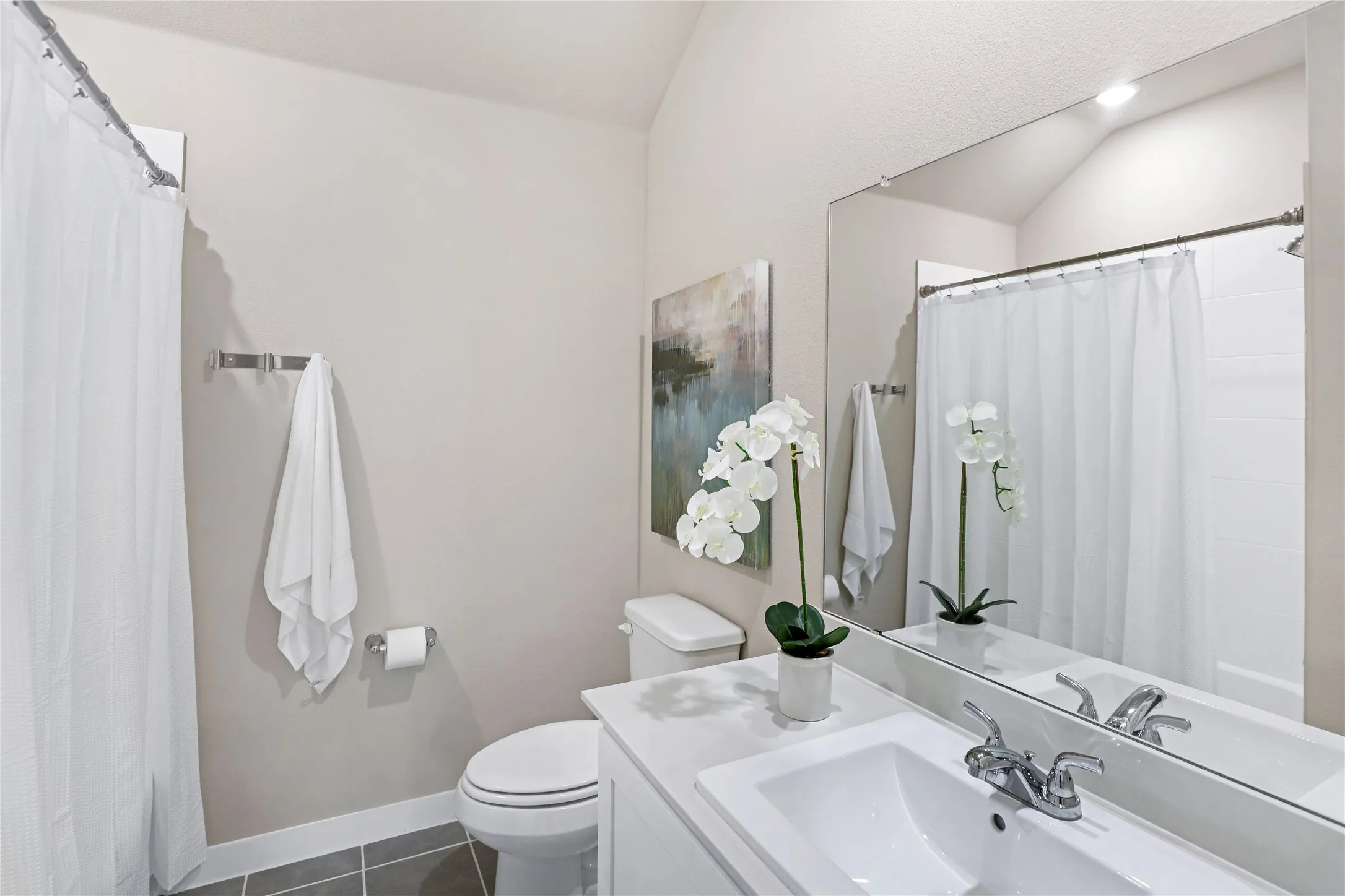 Bathroom featuring a white vanity with integrated sink, chrome faucet, and a large wall-mounted mirror