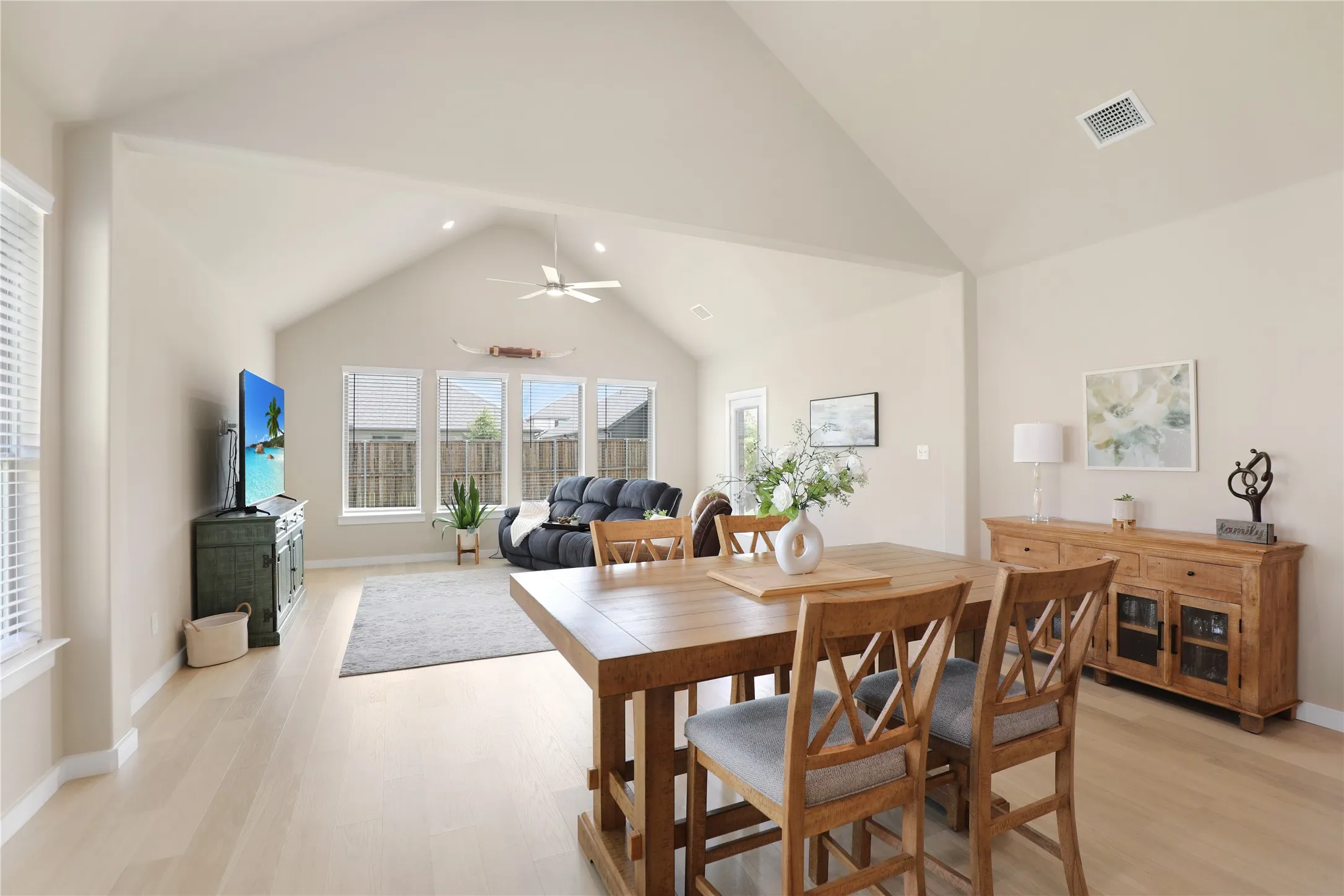 Vaulted ceilings highlight the open-concept living space, featuring light wood-finish flooring and recessed lighting