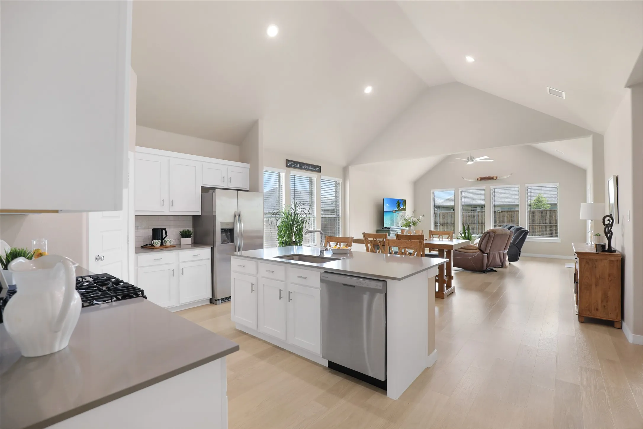 Kitchen featuring white cabinetry, a center island with sink, stainless steel appliances, and light wood-finish flooring
