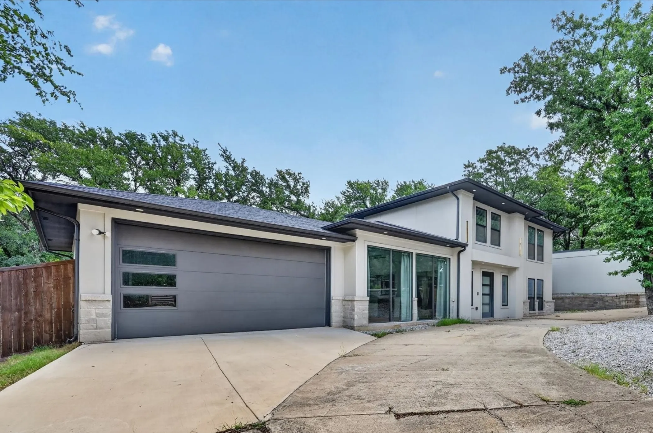 Contemporary exterior featuring a two-story design, a two-car garage with frosted glass panels, and an expansive concrete driveway
