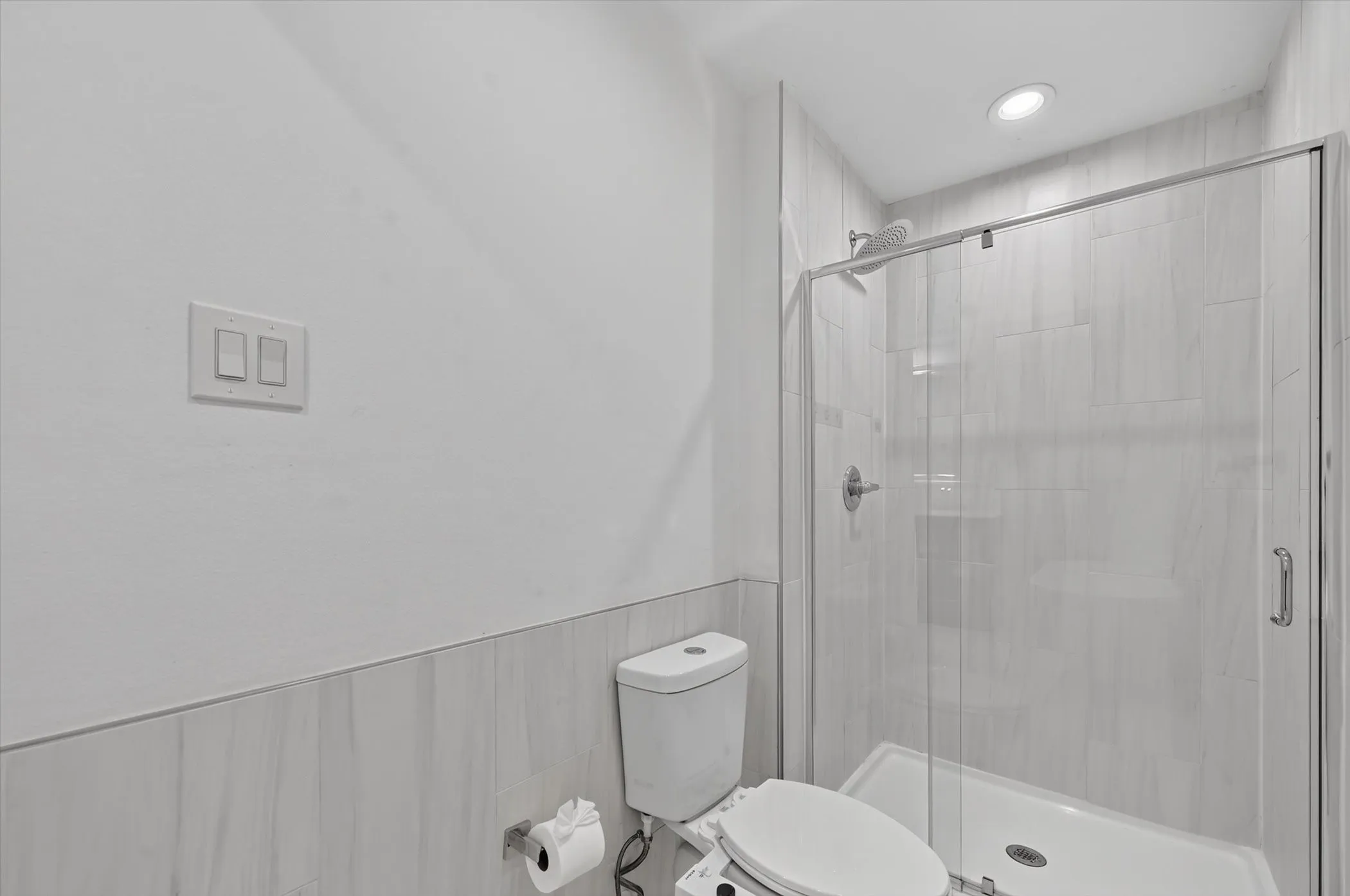 Modern bathroom featuring a glass-enclosed shower with a rainfall showerhead, white subway tile surround, white toilet, and recessed lighting