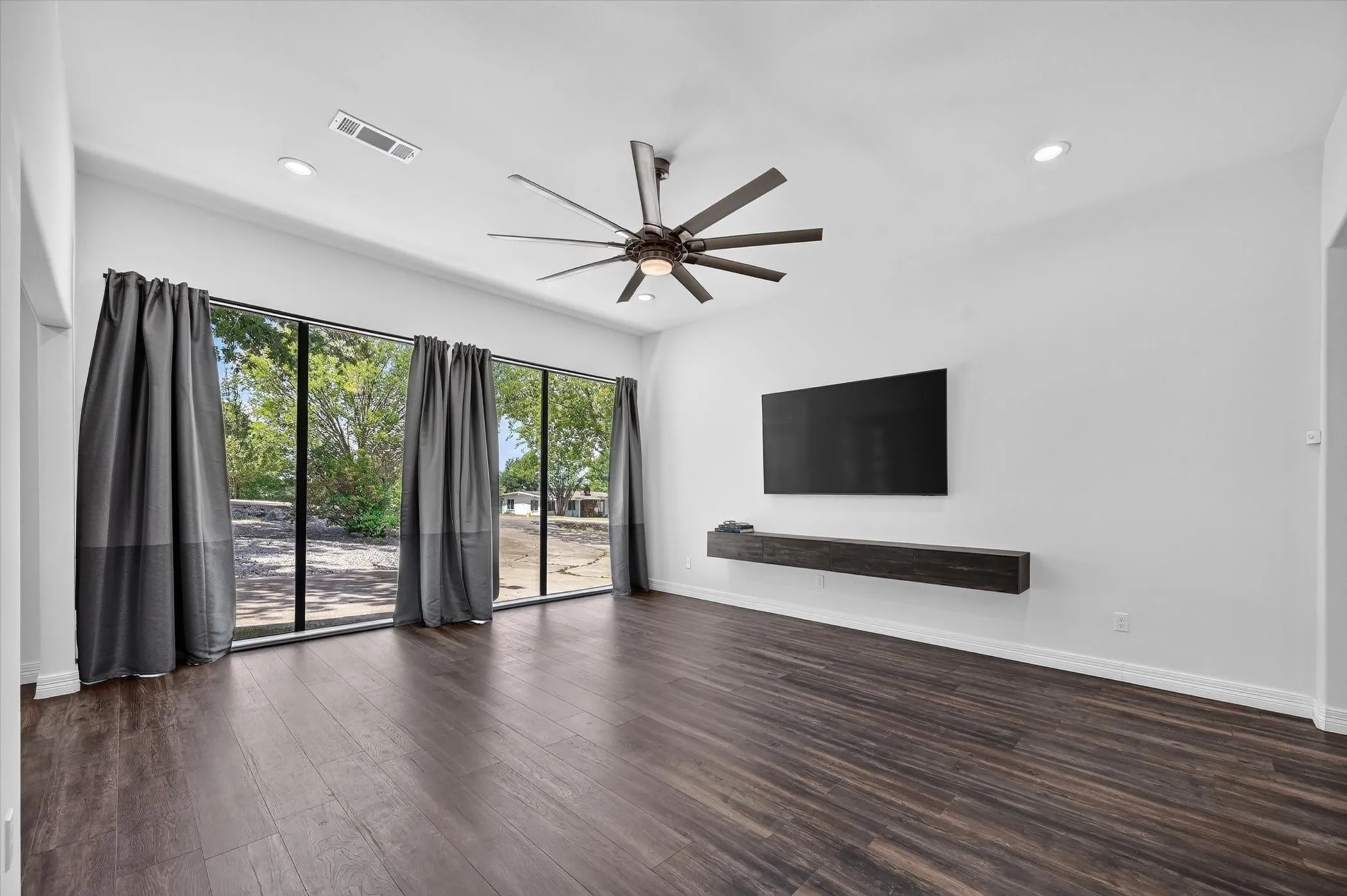 Spacious interior featuring wood-finish flooring, a contemporary ceiling fan, and recessed lighting